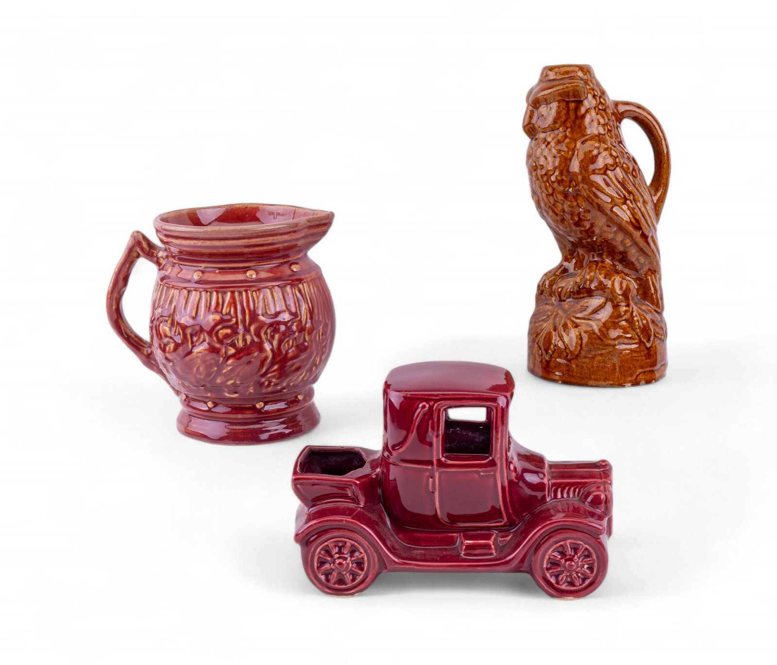 McCoy Car Planter, Owl Jug, and Duck Pitcher: Cranberry glaze duck motif pitcher measuring approx. 7.25" H x 6.25" W x 7.5" D, cranberry glaze antique car planter, and a brown perched owl jug with some loss at base. All unsigned and determined to