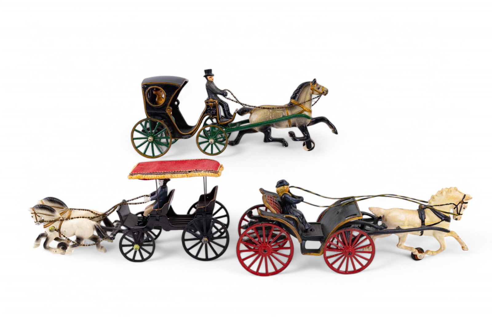 Early 20th C Cast Iron Carriages: Three vintage enamel painted cast iron carriage pull toys featuring a single horse with driver and rider in covered carriage, single horse carriage with one woman driver, and a double horse, double ca