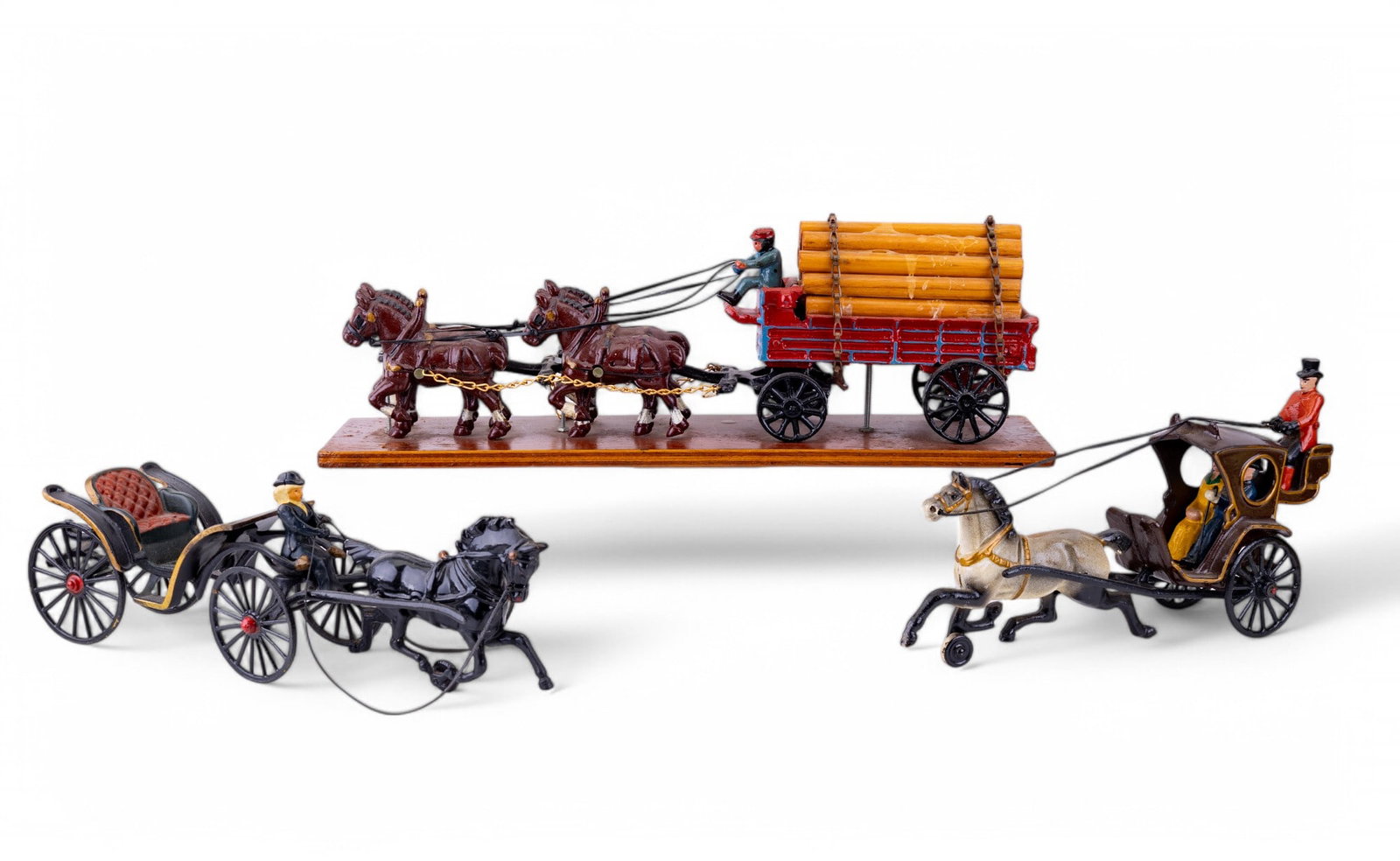 Early 20th C Cast Iron Carriages: Three vintage enamel painted cast iron carriage pull toys featuring single horse with rear seated driver and two passengers in covered carriage, single horse with one rider in open carriage, and four 