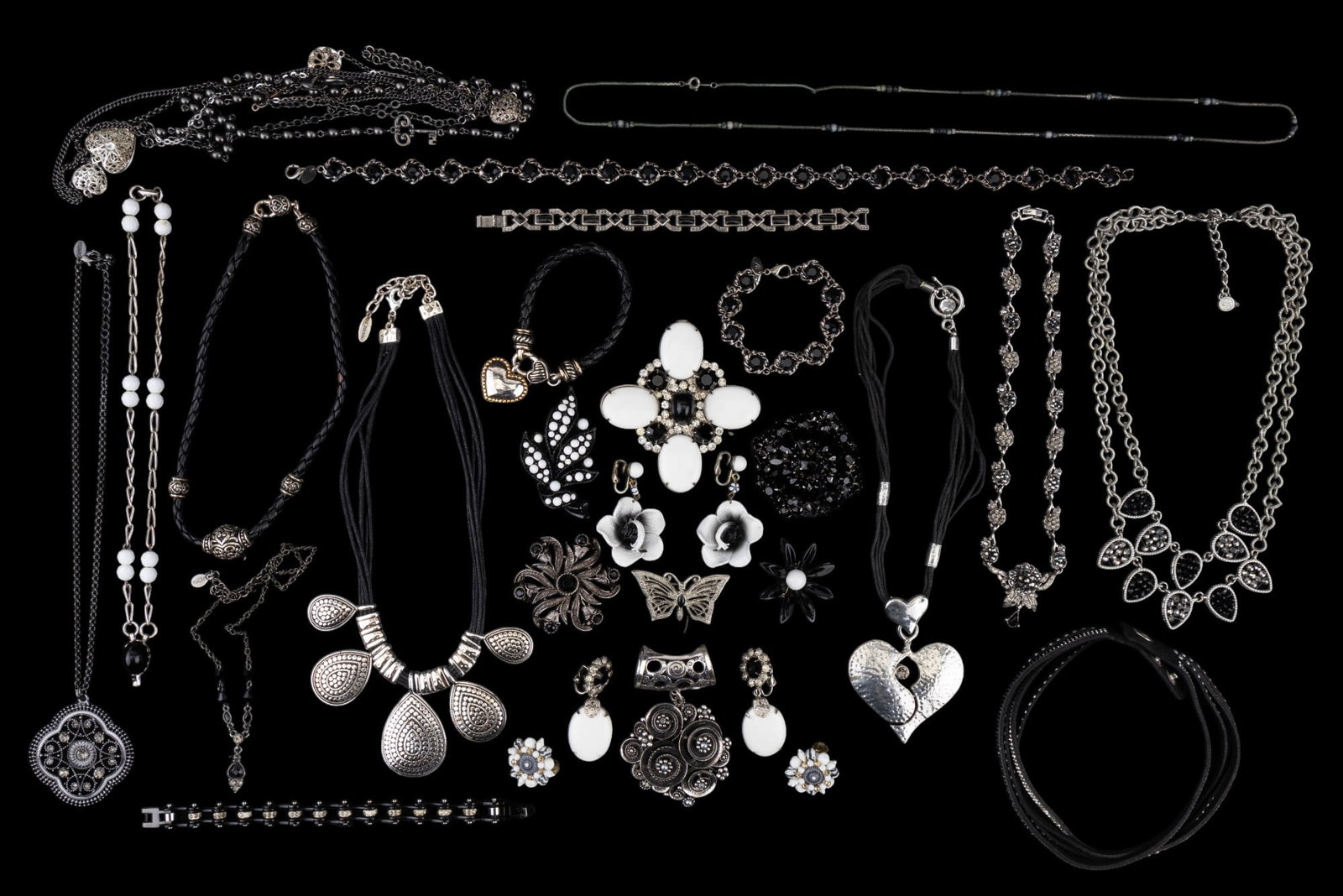 Floral, Statement Jewelry w/ Rhinestone Accents: Assortment of silver tone jewelry w/ black, white, and/or rhinestone accents. Some pieces are gunmetal grey. Grouping includes 12 necklaces, 4 bracelets, 3 pairs of earrings, 1 loose pendant, & 6 broo