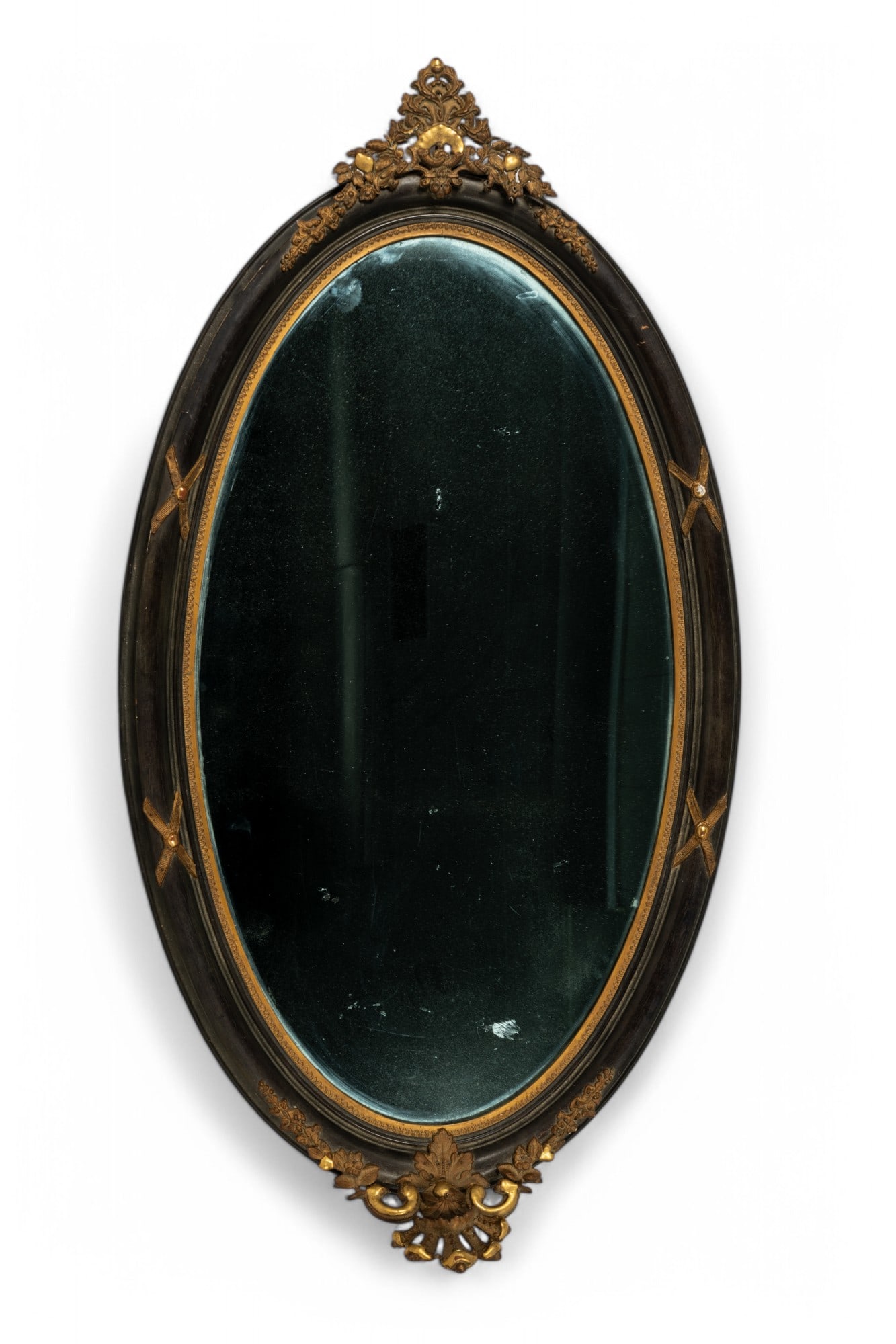 Antique Black Regency Oval Mirror: Antique black Regency mirror with gold tone metal floral ornaments at top and bottom; measures approx. 25.5" W x 45" H. Metal ornaments have wear and loss and reflective surface on reverse have loss.