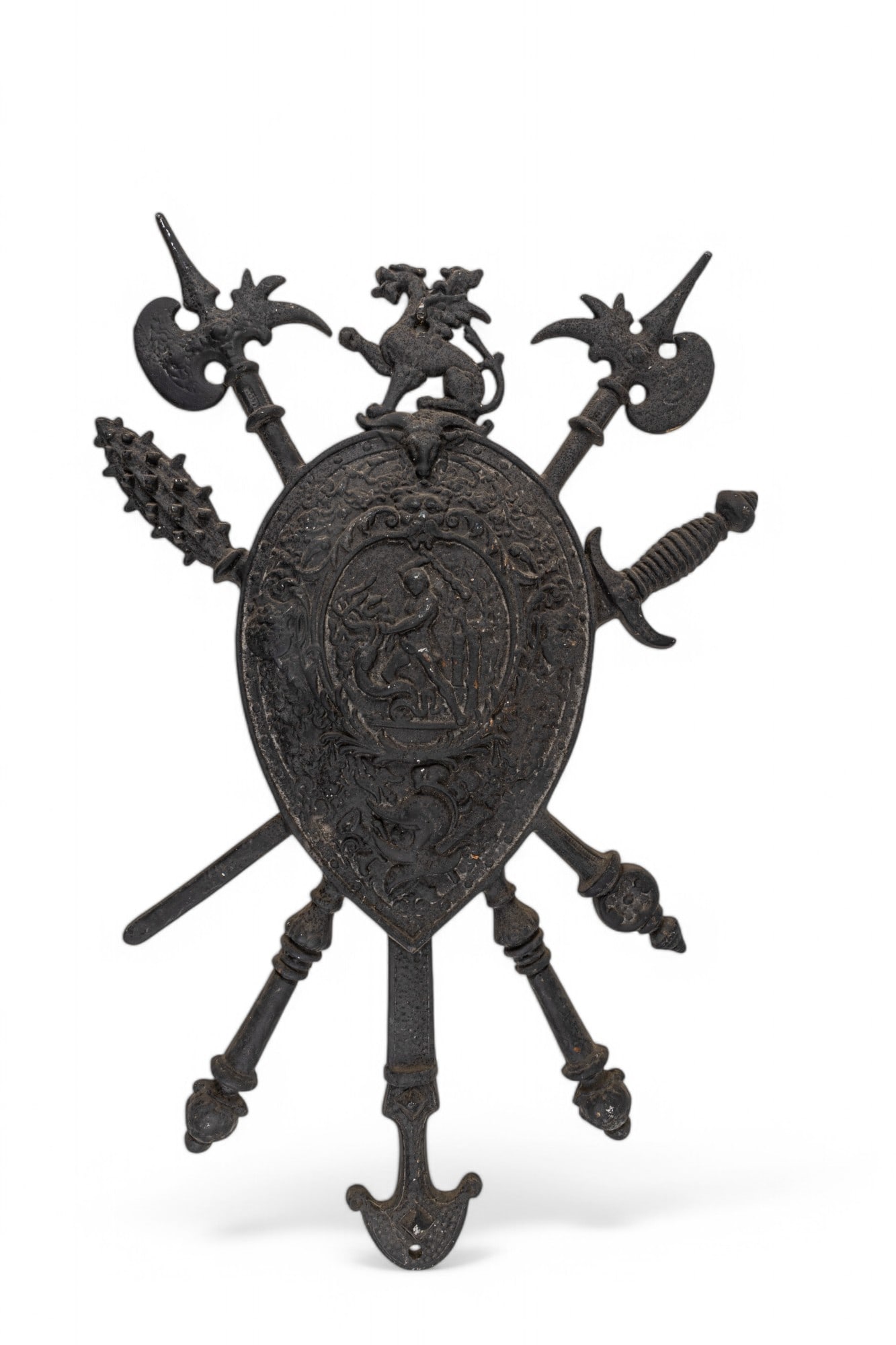 Cast Iron Coat of Arms Plaque?: Cast iron decorative wall plaque featuring a central shield design surrounded by an array of weapon motifs, including swords, axes, and a mace. The shield is adorned with intricate embossed imagery of