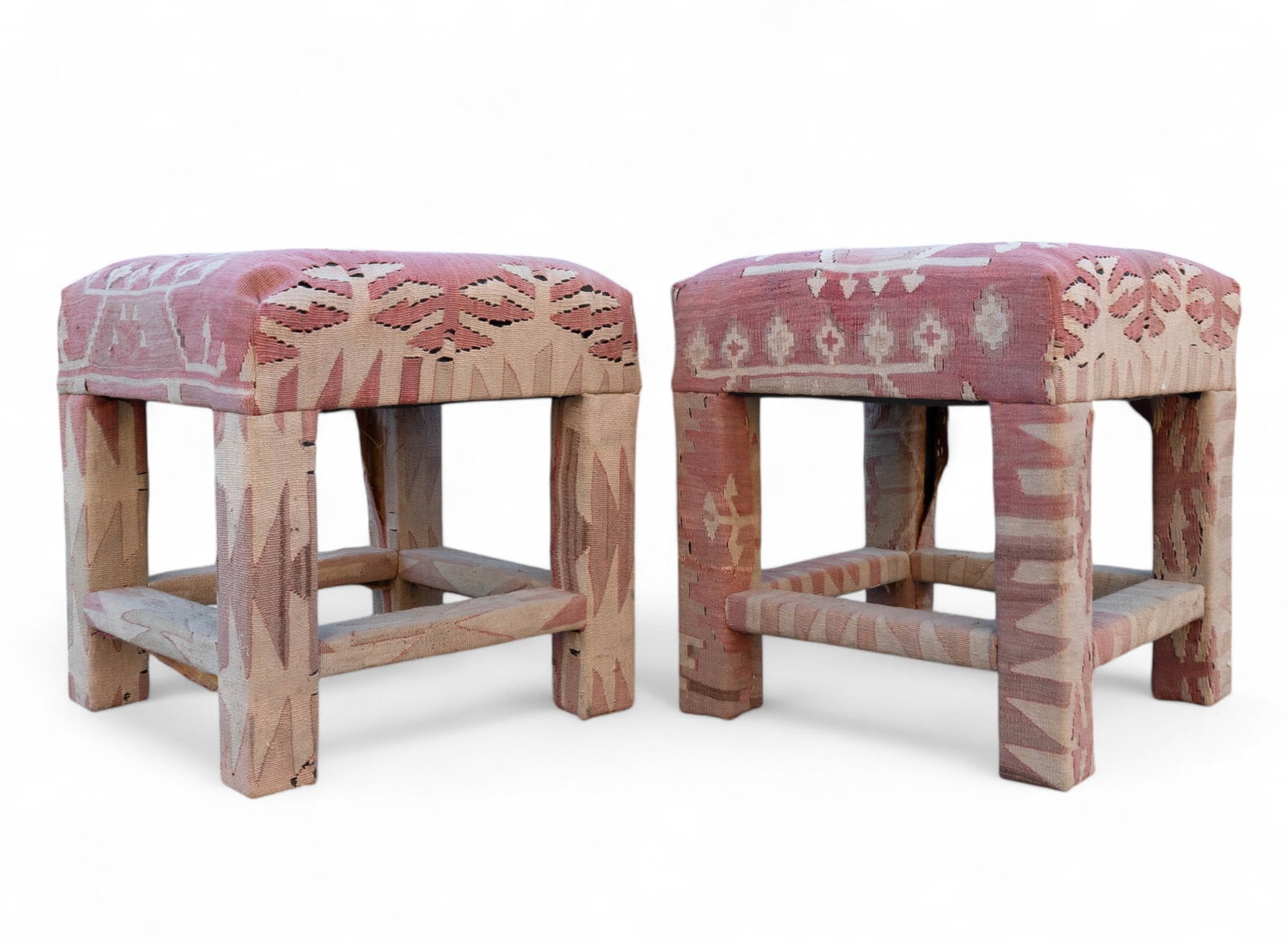 Pair of Kilim-Style Covered Stools: Kilim-style stool pair w/ dull red, tan, ivory, & brown patterns w/ geometric motifs. Stools are approx. 18" tall, 16" wide, & 16" deep. Fabric covers the entire stool. Some wear to fabric on both sto