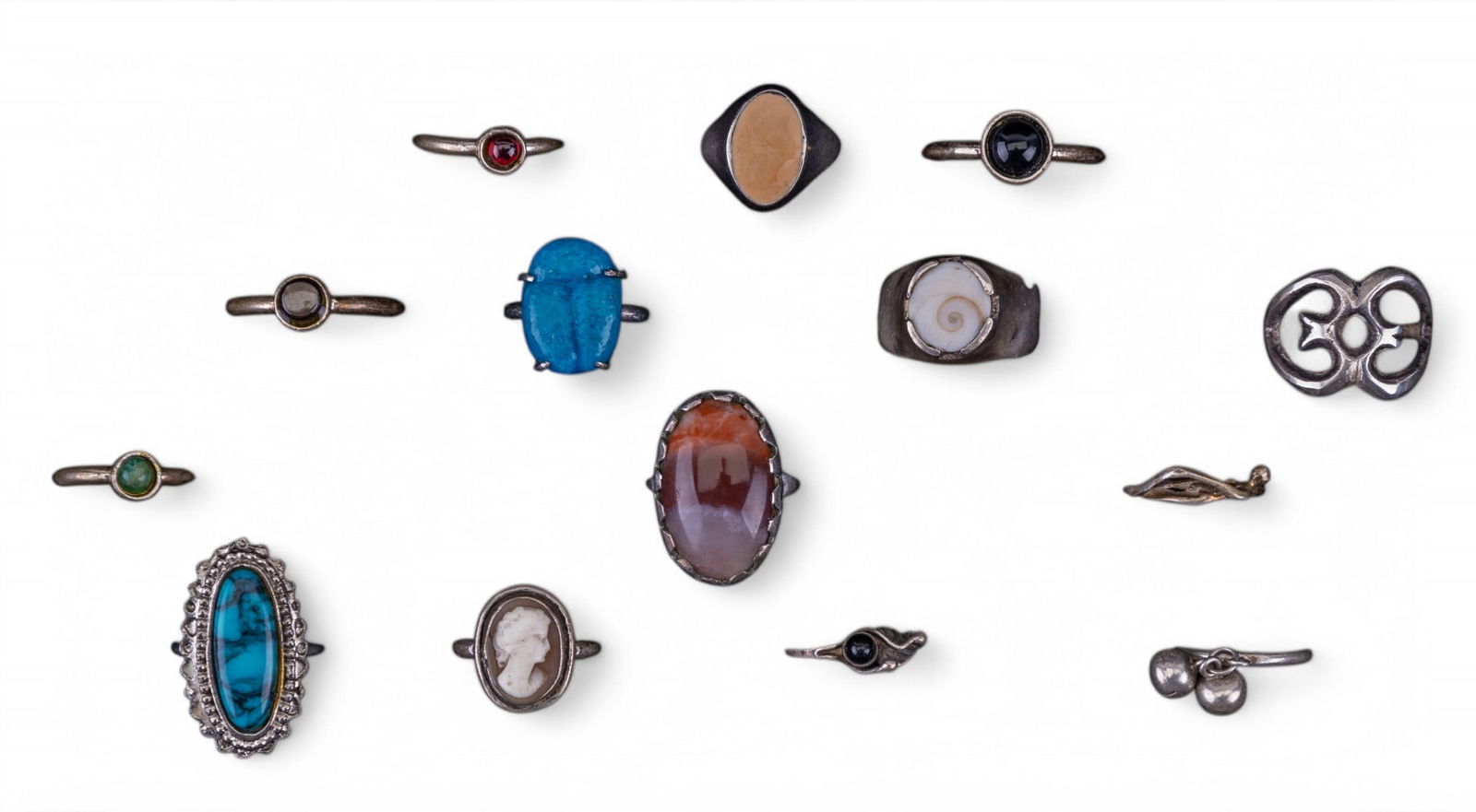 Sterling and Silver Tone Rings: An assortment of 14 rings, ring with simple band and jingle bell charm is sterling, other rings are not marked but include design elements of polished stone, fossil, and vintage cameo, sizes range fro