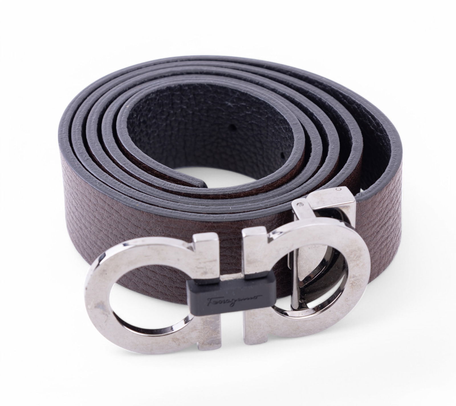 Salvatore Ferragamo Belt w/ Double Gancini Buckle: Salvatore Ferragamo leather belt featuring the iconic double Gancini buckle in polished metal. The belt is crafted from textured brown leather with adjustable length and a metallic-tone buckle engrave