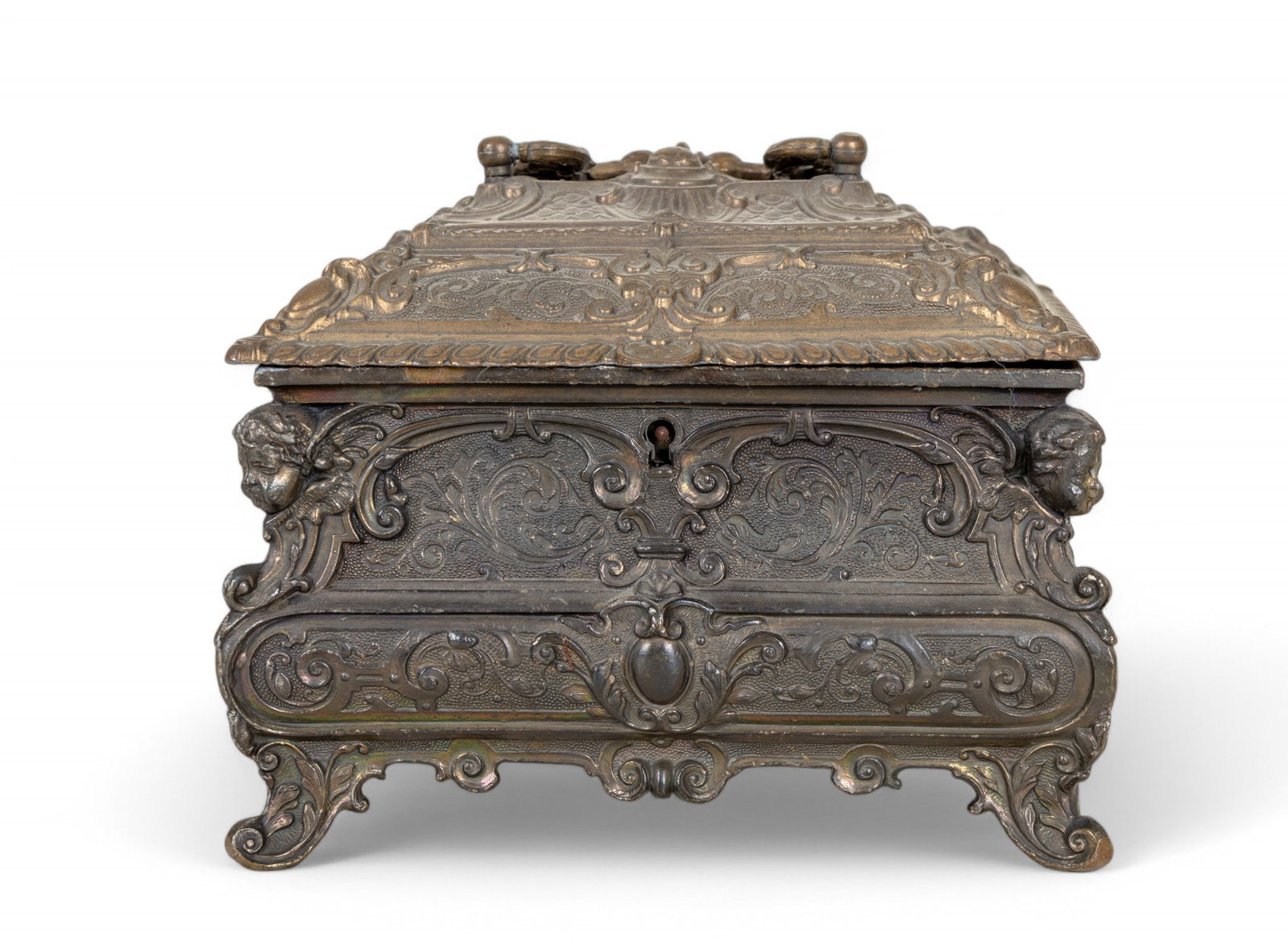 Cast Metal Jewelry Casket: Ornate cast metal jewelry casket w/ red felt interior. Design features botanical motifs & sculpted cherub heads at each corner. Piece measures approx. 5.75" tall (handle down), 7" wide, & 5" deep. Key
