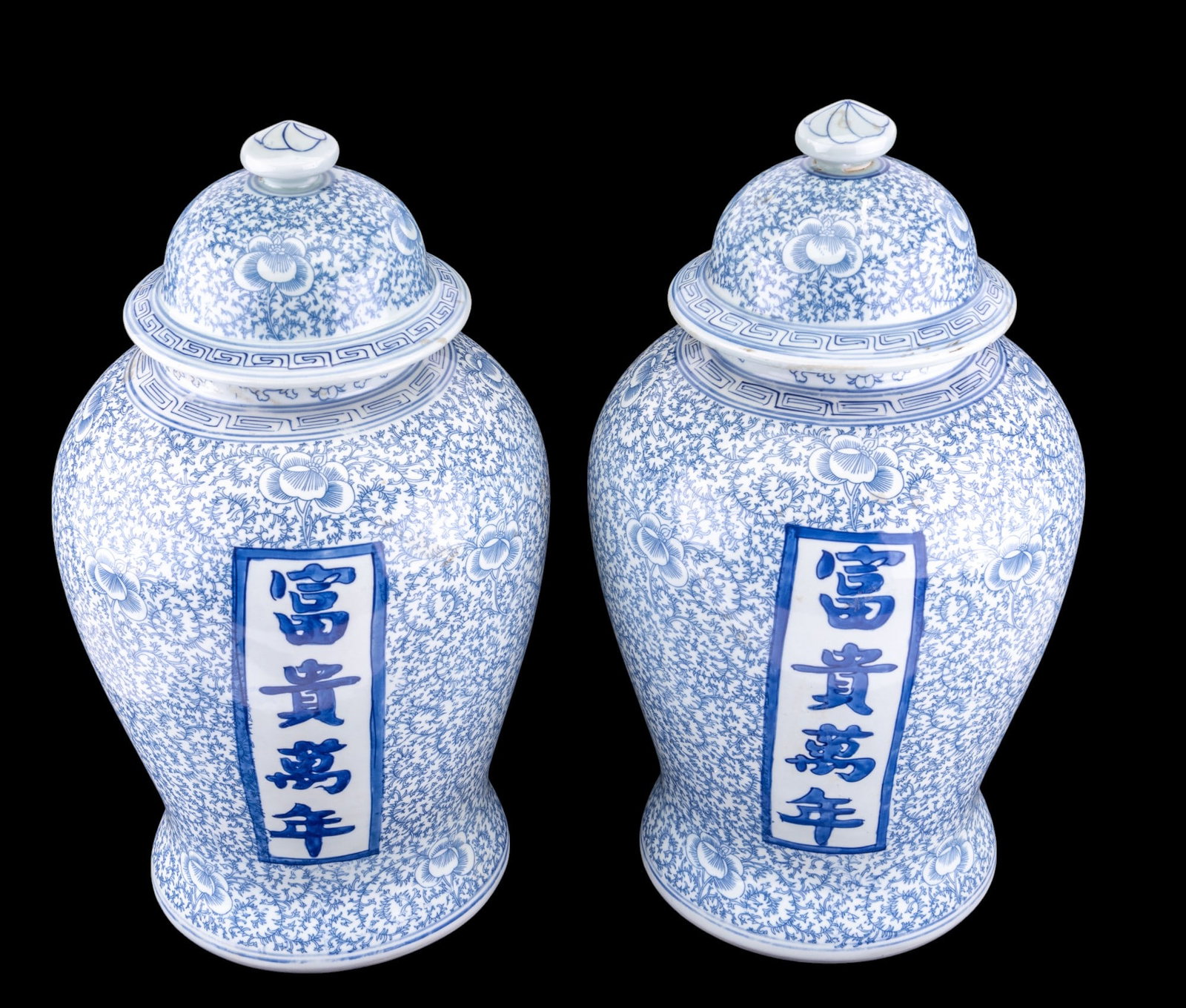 Chinese Blue & White Porcelain Temple Jar Pair: Pair of Chinese blue & white porcelain temple jars / urns w/ lids. Design features flower & vine motifs, geometric patterns on the lid & below the rim of the jar, & text on 2 sides that translates to