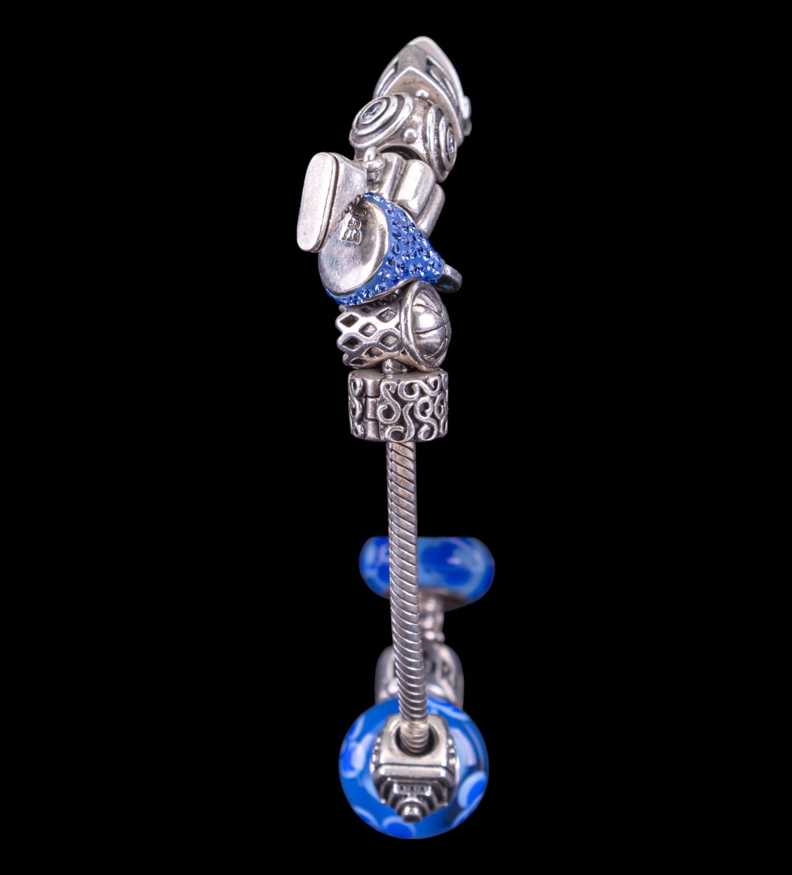 Sterling Silver Pandora Charm Bracelet (11 Charms): Sterling silver Pandora charm bracelet w/ 11 charms including blue beads, a basketball in a hoop, a sneaker, a Hershey's Kiss w/ blue rhinestones, a ship, & more. Bracelet measures approx. 2.5" in dia