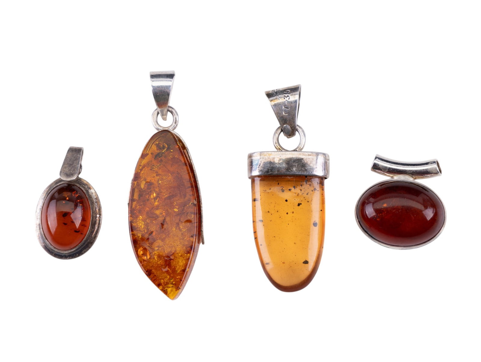 Sterling and Amber Estate Pendants (4): Four sterling silver amber pendants featuring two oval cabochons, large marquis shaped crystallized pendant, and a drop pendant marked Mexico 925.