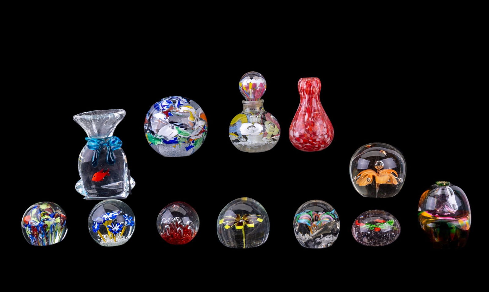Blown Glass Paperweights and Vessels: A collection of 10 blown glass art paperweights featuring a large spherical paperweight made in the Czech Republic, a figural blown glass goldfish in a bag, a red blown glass bud vase, a floral blown
