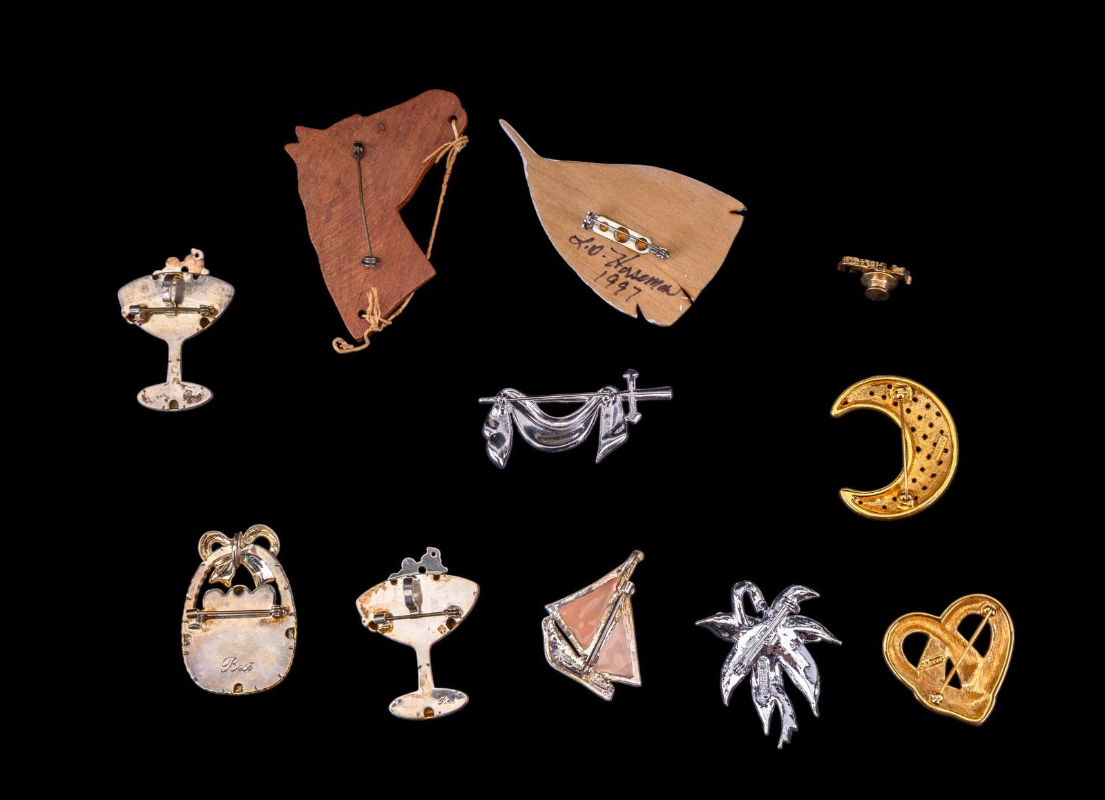 Vintage Best, Monet, Handcarved, more Brooches: Grouping of costume jewelry brooches including three vintage Best brooches (as photographed), a vintage Best enamel sailboat brooch, a silver tone a blue stone brooch marked "Ora", Monet gold tone hea