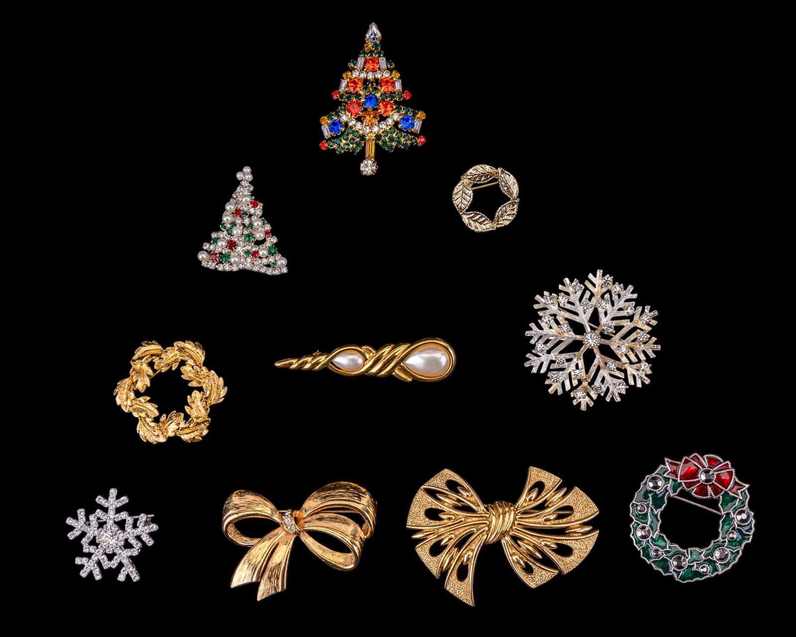 Christmas, Winter Themed Vintage Brooches, more: Grouping includes a vintage multicolored rhinestone Christmas tree brooch, a vintage Monet ribbon style large gold tone brooch, an Avon gold tone ribbon brooch, a Napier gold tone wreath brooch, Marve