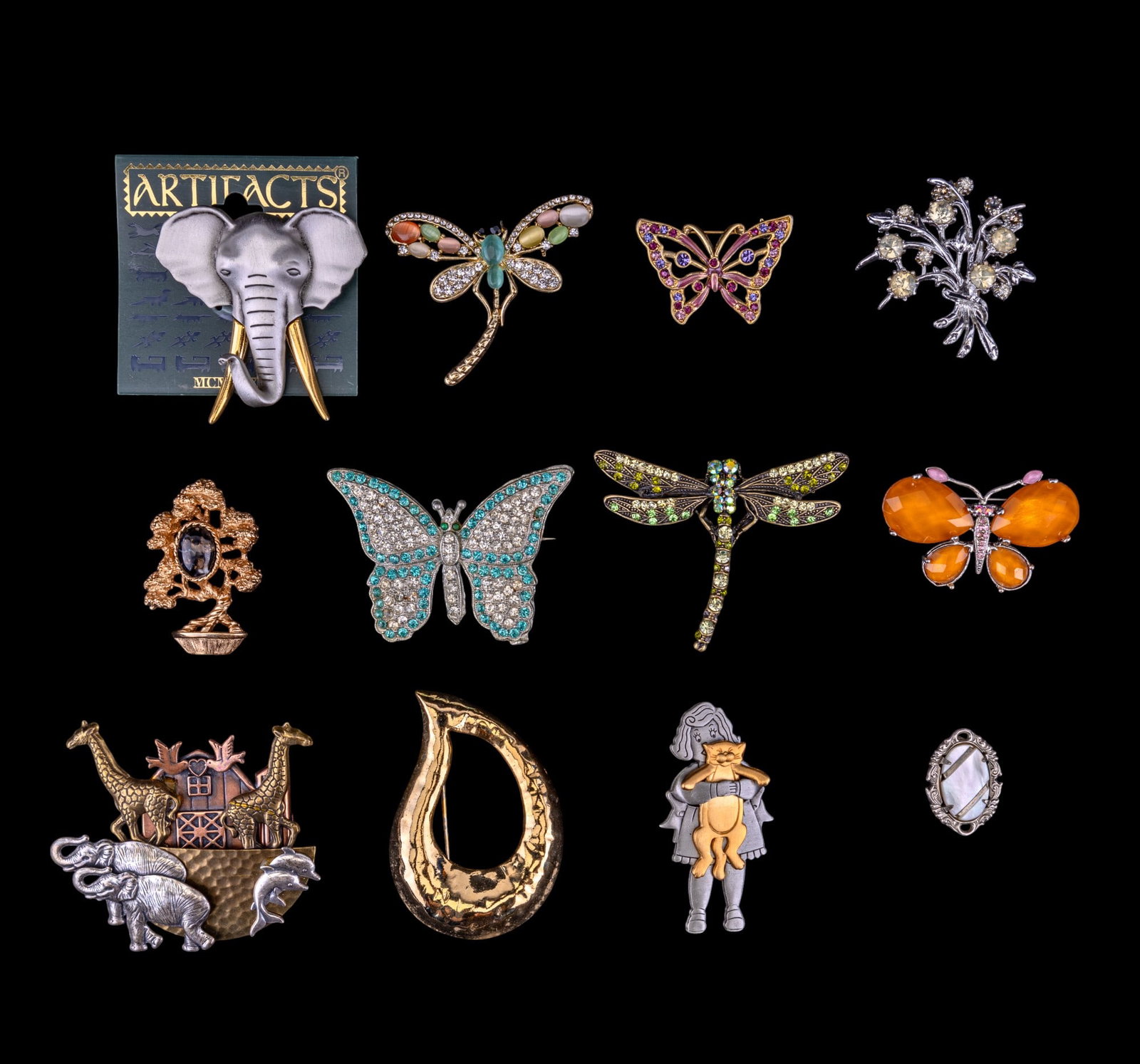 Vintage Brooches Including Jonnette Jewelry: A collection of vintage brooches featuring diverse designs. Includes a JJ (Jonnette Jewelry) brooch of a woman holding a cat and an Artifacts elephant brooch. Additional pieces in the collection are a