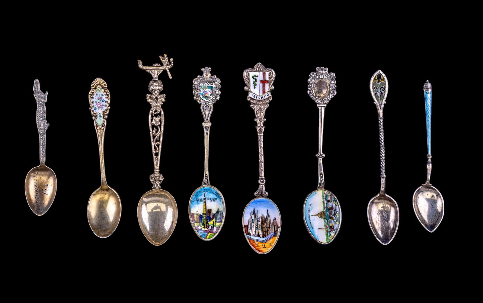 Sterling Silver Souvenir Spoons: An assortment of 8 sterling silver souvenir spoons featuring Jacksonville, FL, Washington D.C., Indiana, and Milan, Italy, antique enamel spoons, including a stained glass motif enamel handle.