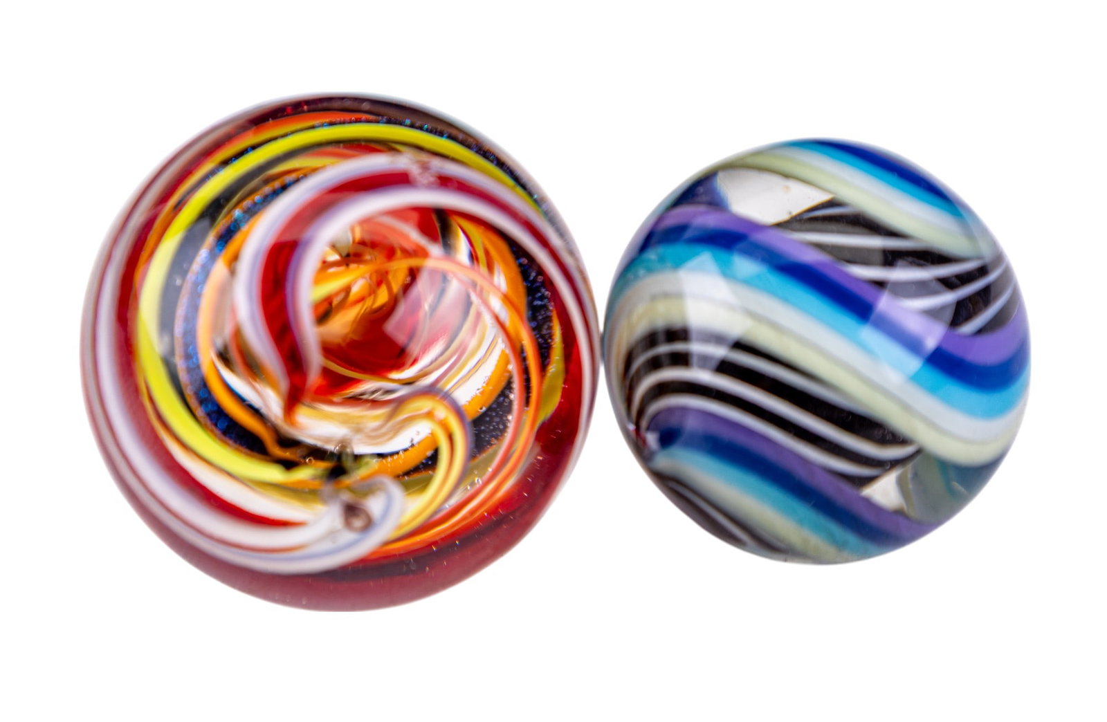 Handcrafted Marbles (2): 2 handcrafted marbles, 1 larger than other. Larger marble has vibrant mix of colors including red, yellow, and blue arranged in a swirl pattern, smaller marble has swirls of blue, black, white, and pu