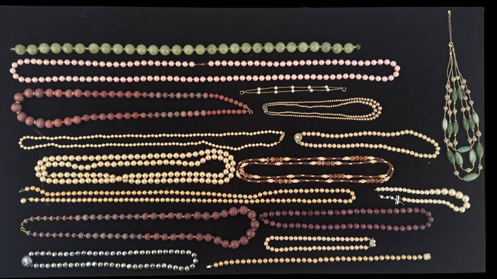 Pearl, Pearl Bead, Wood Bead, and Other Necklaces: A collection of faux and real pearl necklaces, wood bead, and plastic bead necklaces featuring a vintage two strand champagne colored graduated pearl necklace with a sterling safety clasp, a vintage L