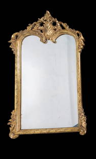Ornate Rococo Style Wall Mirror: An ornate Rococo style wall mirror with scrollwork, floral detailing, and a gilded wood frame. Mirror measures approx. 60.5" H x 33" W