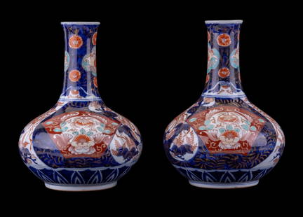 Japanese Imari Porcelain Bottle Vases (2): A pair of Japanese Imari porcelain bottle vases, each with bulbous bodies and flaring necks. Decorated in a traditional palette of blue, iron red, and gilt with chrysanthemums, phoenix birds, and styl