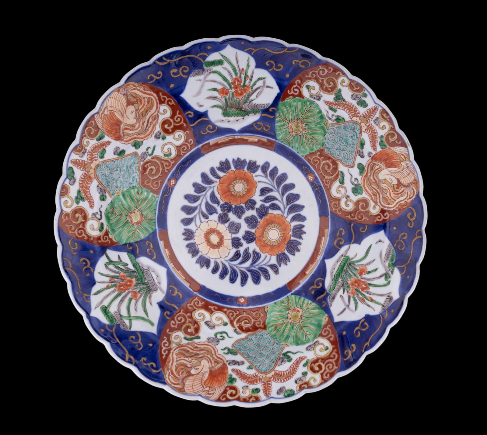Japanese Imari Charger Plate: A large Japanese Imari porcelain charger plate with scalloped edges and a bold central floral medallion surrounded by alternating panels of stylized chrysanthemums and garden scenes. Reverse displays 