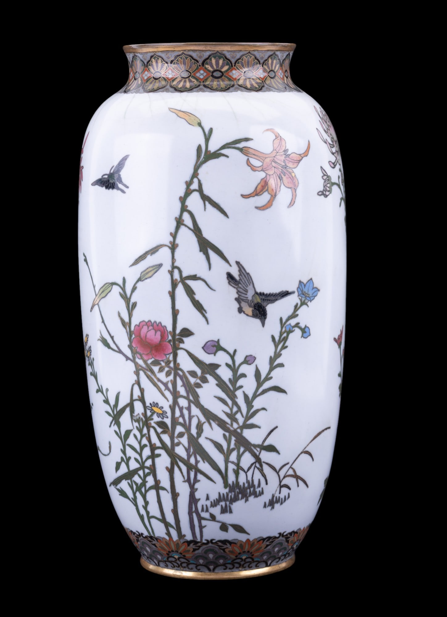 Japanese Cloisonne Enamel Cylindrical Vase: A Japanese cloisonne enamel vase in cylindrical shape with detailed wirework on a grey background, decorated with birds, butterflies, and colorful flowers amidst stems and leaves. Measures approx. 13"