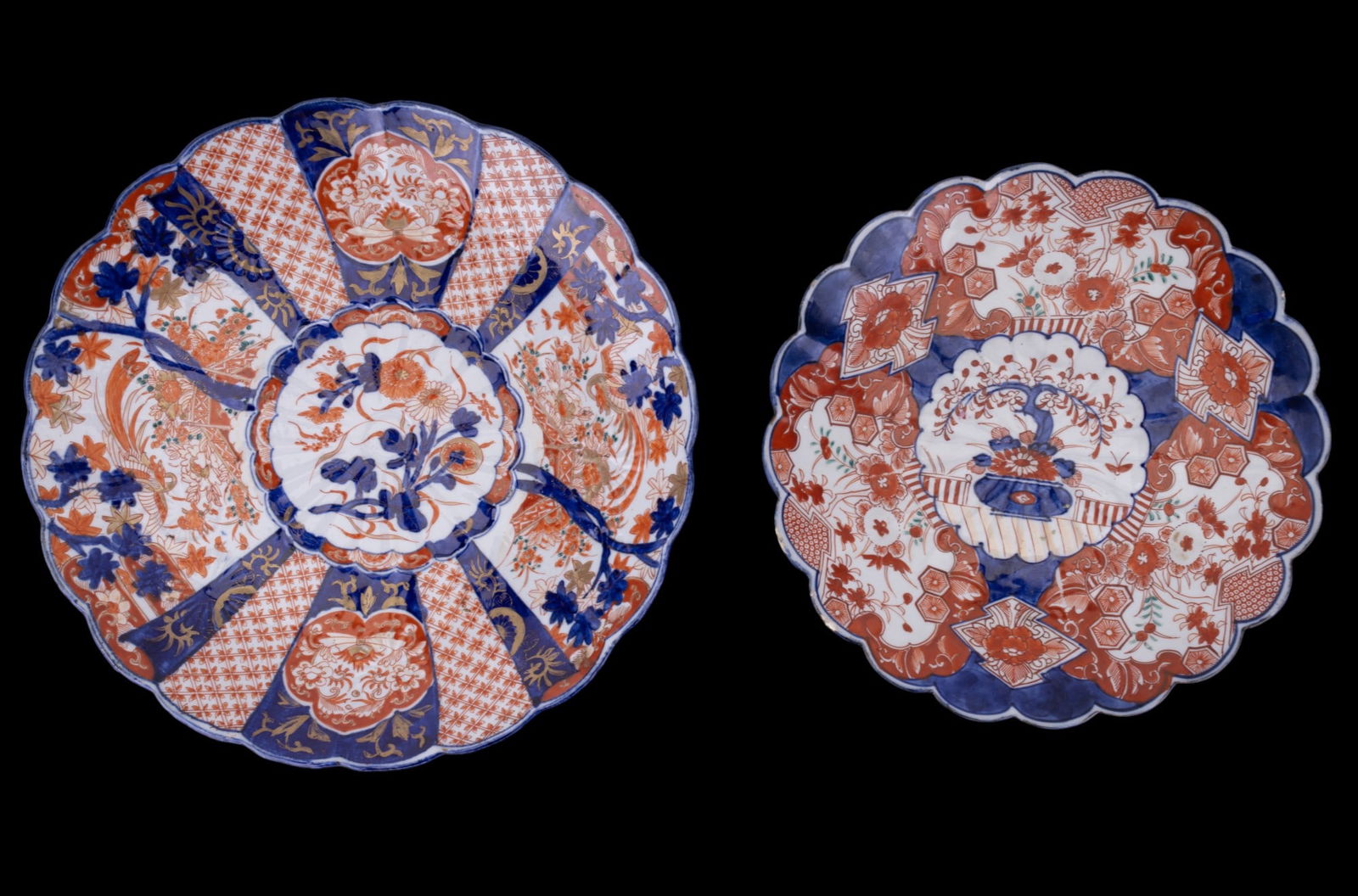 Antique Japanese Imari Charger Plates (2): A pair of antique Japanese Imari porcelain chargers, each richly hand-painted in iron red, cobalt, blue, and gilt with scalloped edges. One features alternating fan- shaped panels with maple and chrys