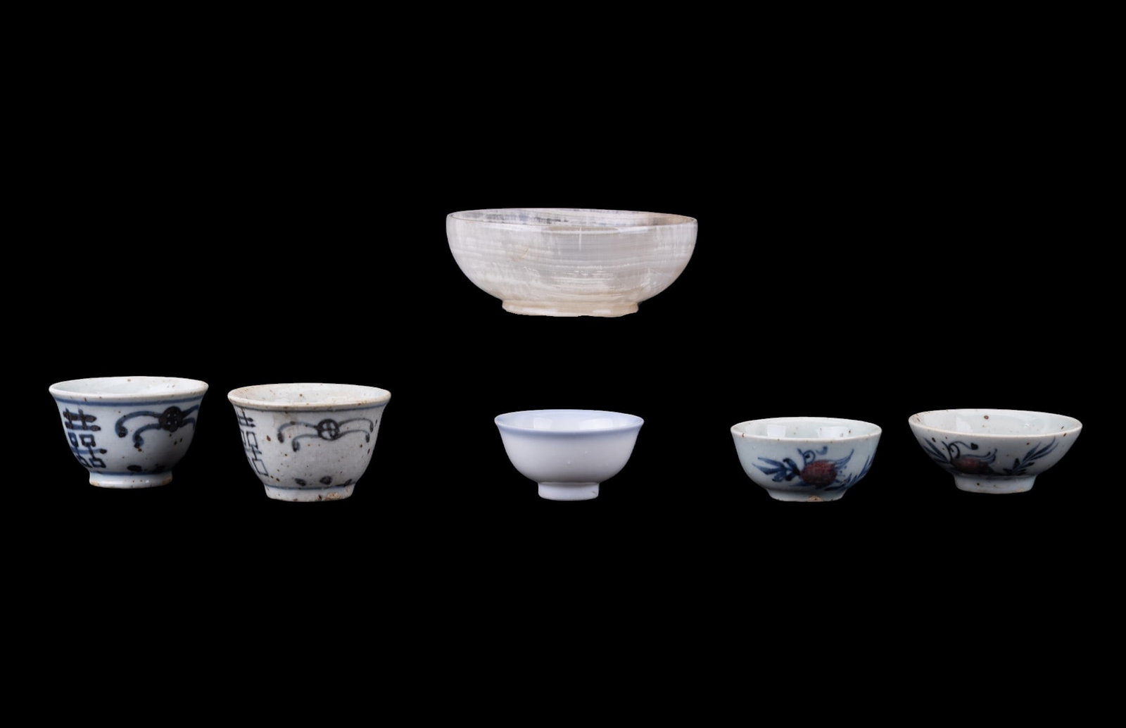 Imperial Japanese and Qing Porcelain Cups: A collection of porcelain cups featuring an Imperial era Japanese ochoko (sake cup), two Qing style porcelain double happiness tea cups, two Chinese porcelain tea cups depicting blue and white motifs