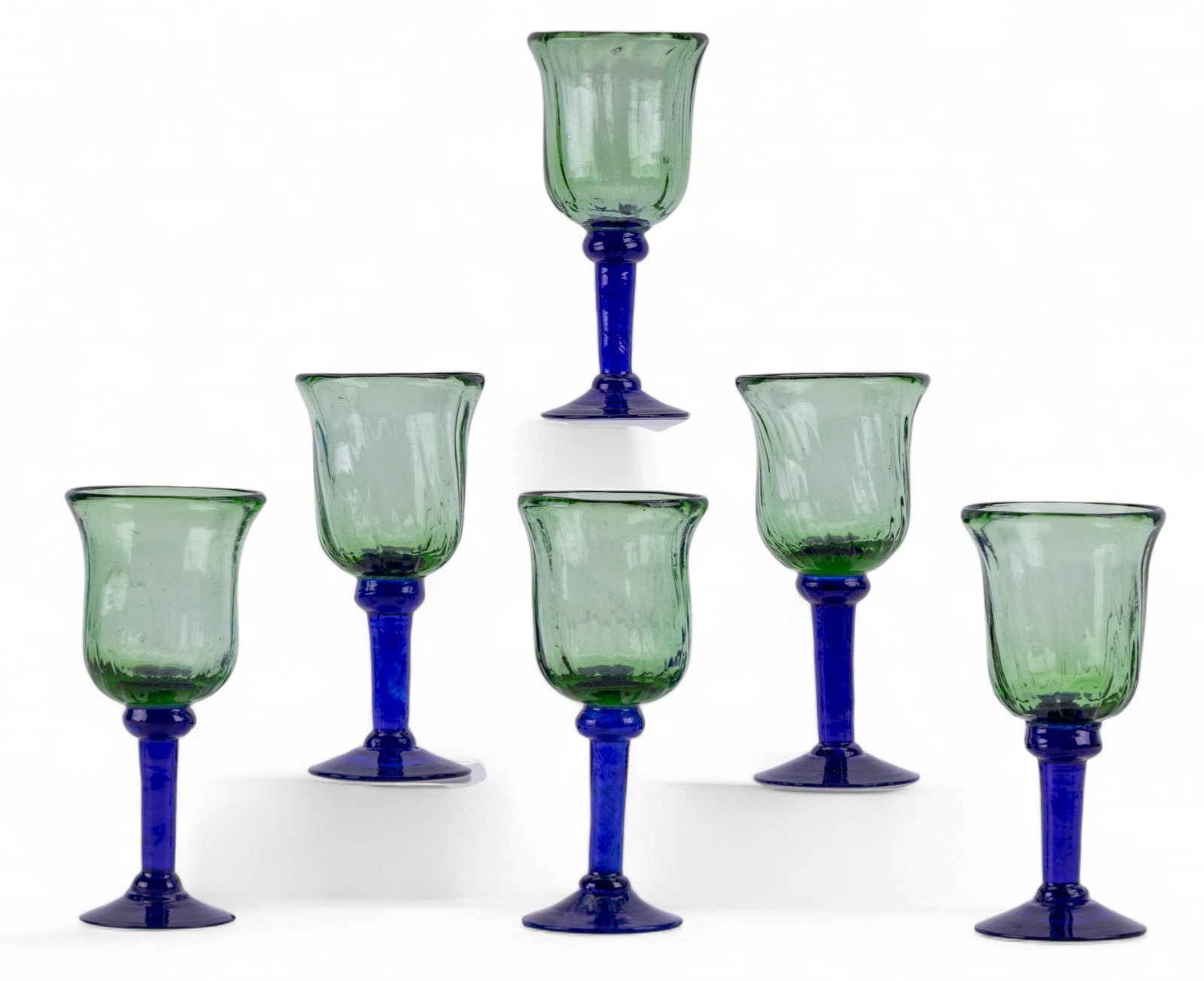 Artisan Hand-Blown Wine Glasses: A set of 6 artisan hand-blown wine glasses with flared green bowls and blue stems and bases. Each glass exhibits slight variation in form. Each measures approx. 8" H. Condition is as seen in photos.
