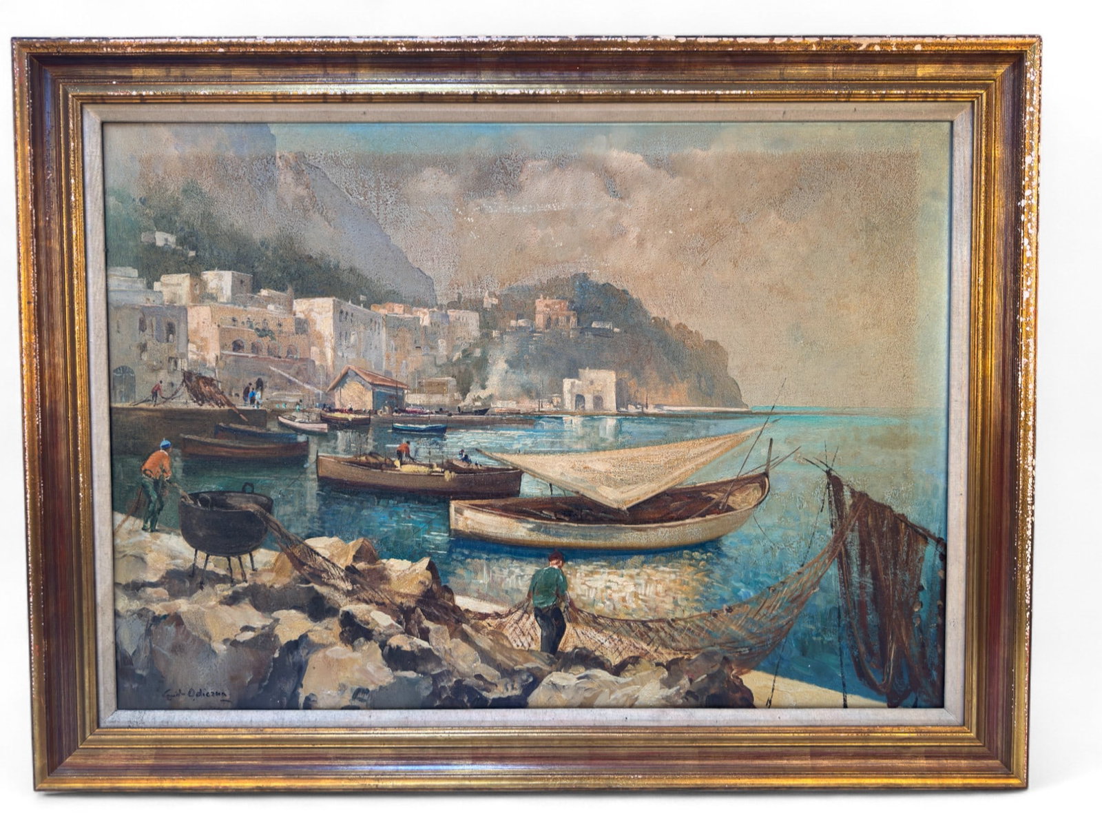 Signed Guido Odierna (Italy 1913-1991) O/C: A signed oil on canvas painting by Italian artist Guido Odierna (1913-1991) depicting a Mediterranean harbor with fishing boats, figures mending nets, and a backdrop of costal architecture and cliffs.