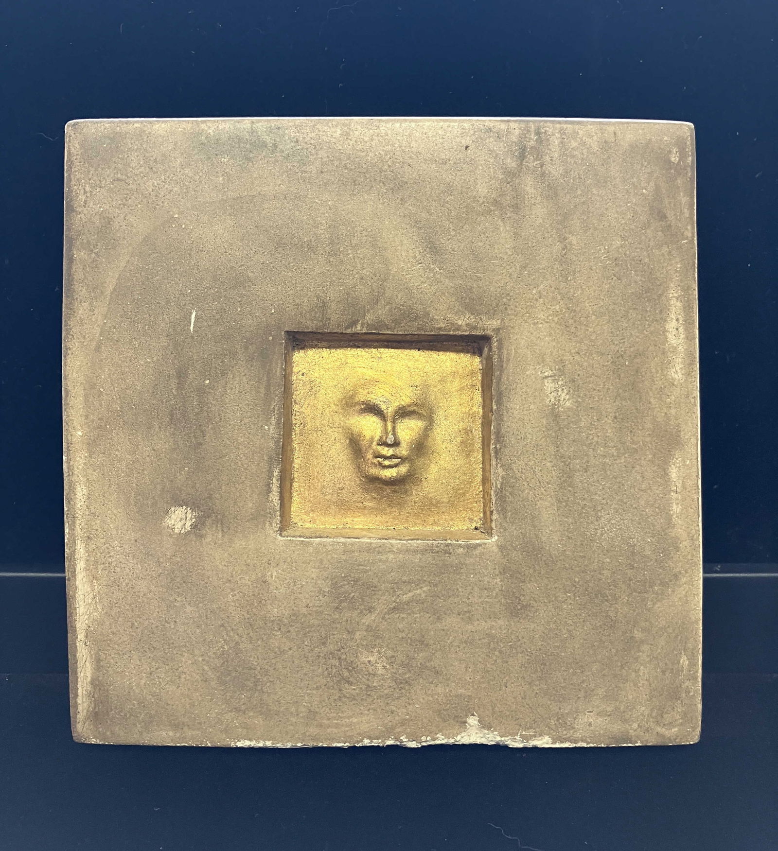 Marlo Gold Face Sculpture / Tile ~6"x 6": This square piece of clay / ceramic tile has an inset square with a face painted gold . It is signed on the bottom edge copyright Marlo and measures approx 6" x 6" x 1" D.