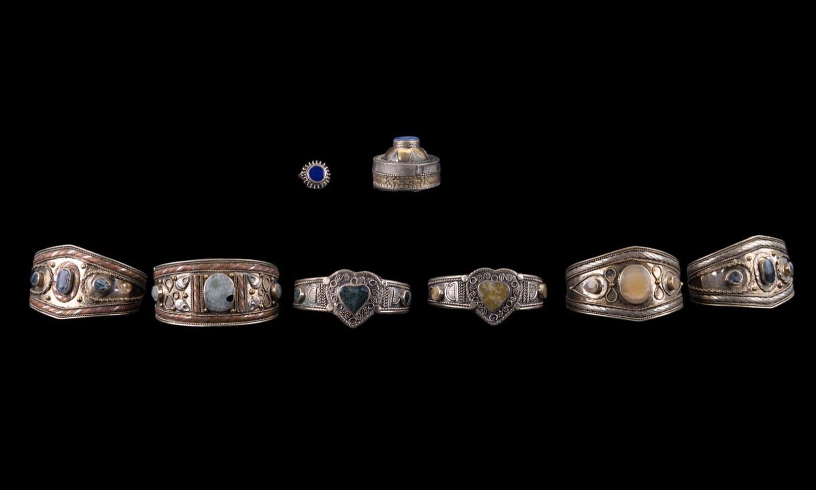 Afghan Tribal Handmade Bracelets & Ring: A collection of 7 handcrafted Afghan tribal jewelry pieces, including six ornate mixed-metal cuff bracelets set with various polished stones, and 1 domed ring with a blue stone. Each piece features tr