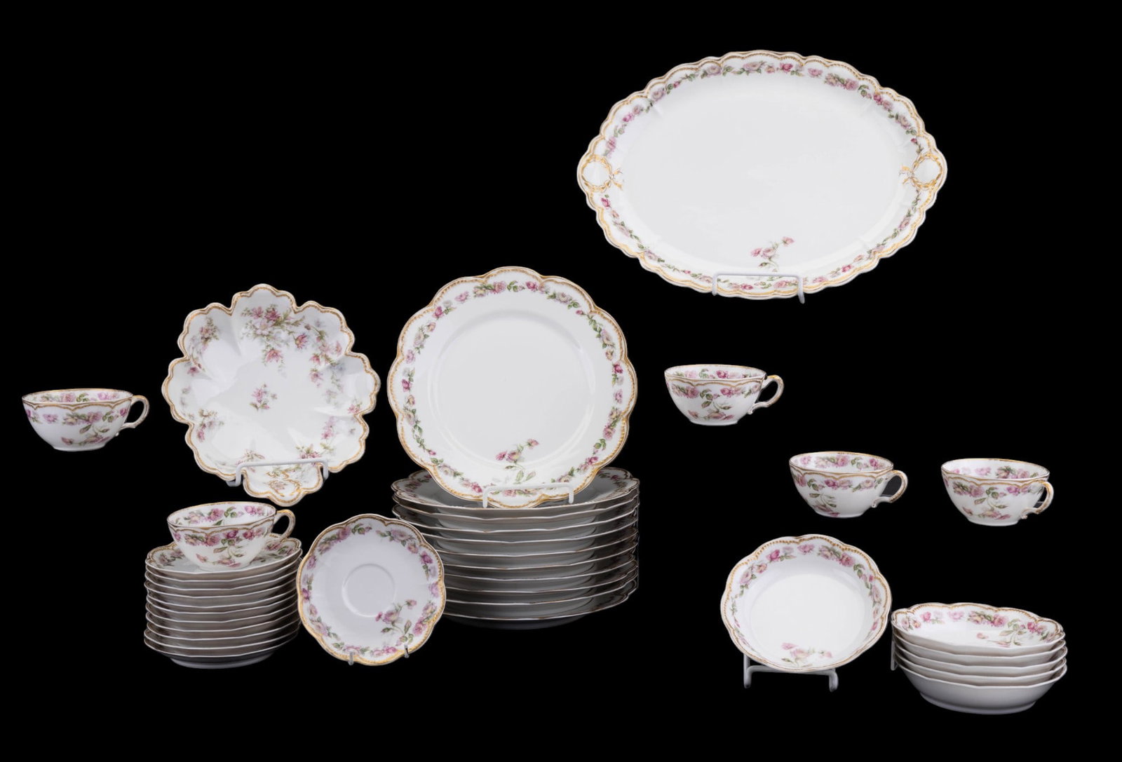 Haviland Limoges Porcelain Set Floral Pattern: A Haviland Limoges porcelain set including twelve saucers, eleven dinner plates, six small bowls, a serving plate and serving bowl, and five teacups. Items with floral pattern and gold painted rim.