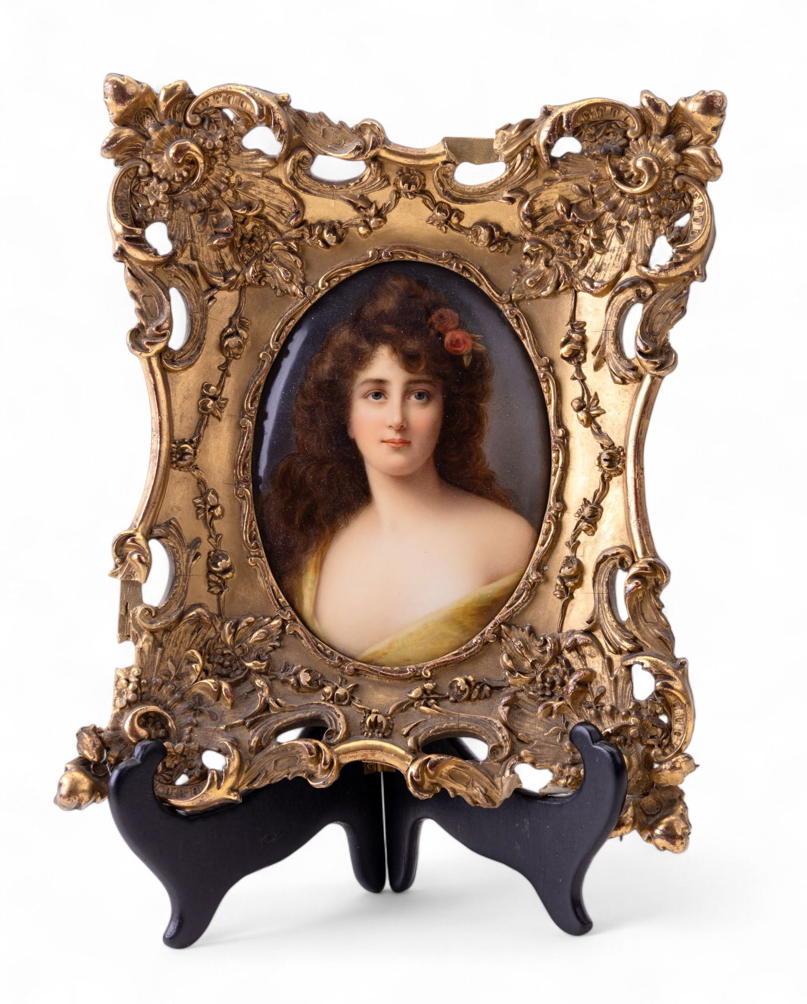 KPM Painted Porcelain Plaque: Ornate gilt wood framed oval shaped KPM painted porcelain plaque depicting a young brunette woman with roses in her hair, note some wear to frame, plaque measures approx. 5" W x 6" H.
