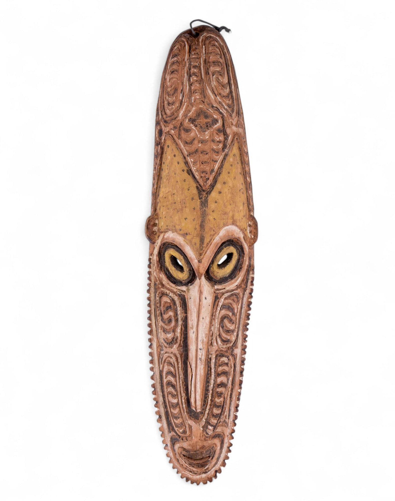Papa New Guinea Carved Wooden Tribal Mask: Elongated carved wood mask from Papua New Guinea, featuring a long projecting nose, circular eyes with painted details, and incised linear designs throughout. Measures approx. 23.75" H x 5.5" W.