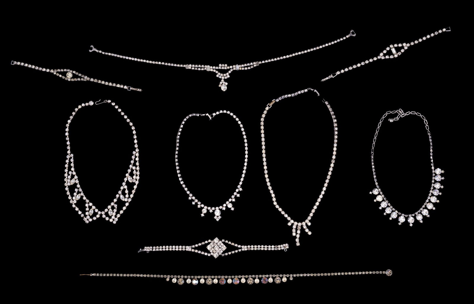 Kramer and Other Rhinestone Jewelry: Rhinestone jewelry, including necklaces, bracelets. The pieces vary in design and feature various arrangements of clear and iridescent rhinestones. One clasp possibly broken and one bracelet marked Kr