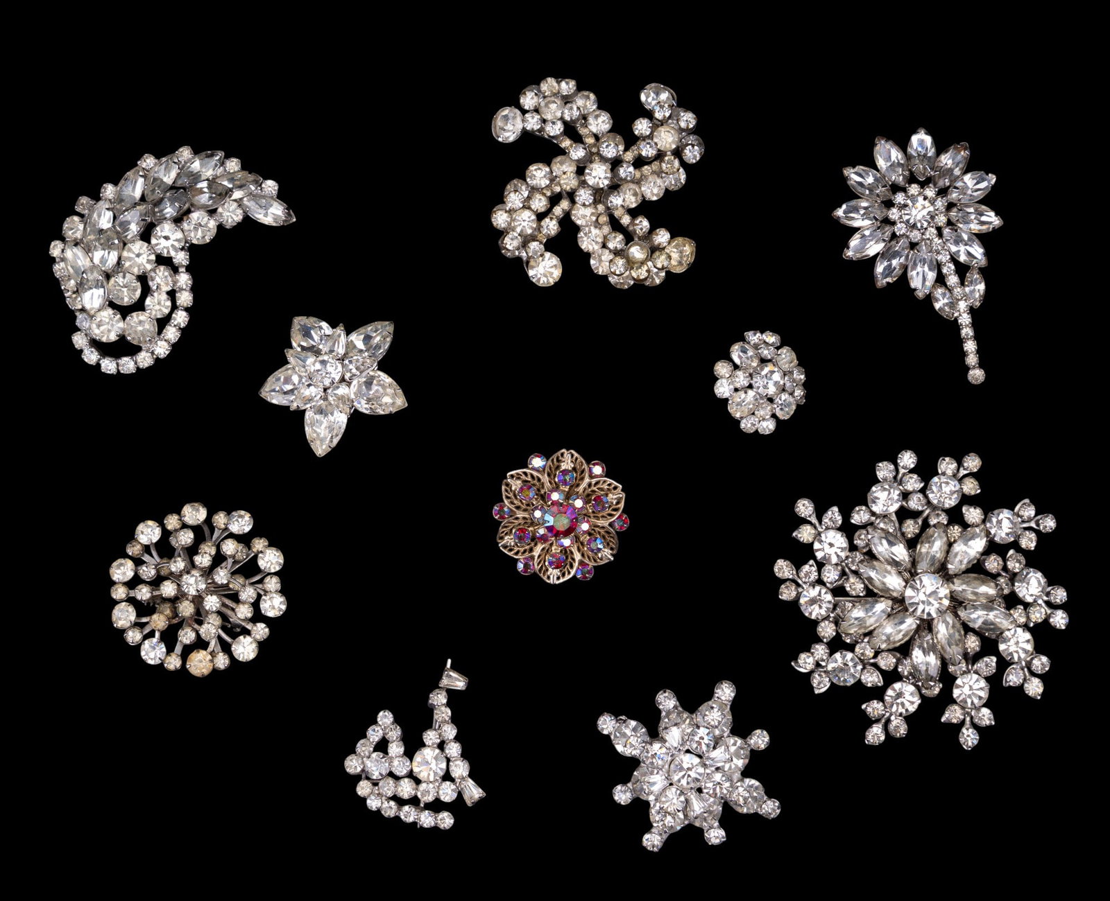 Vintage Rhinestone Brooches and Pins: Ten vintage brooches and pins featuring rhinestone embellishments. Includes various designs such as floral, circular, and abstract patterns, with clear and multicolored rhinestones.