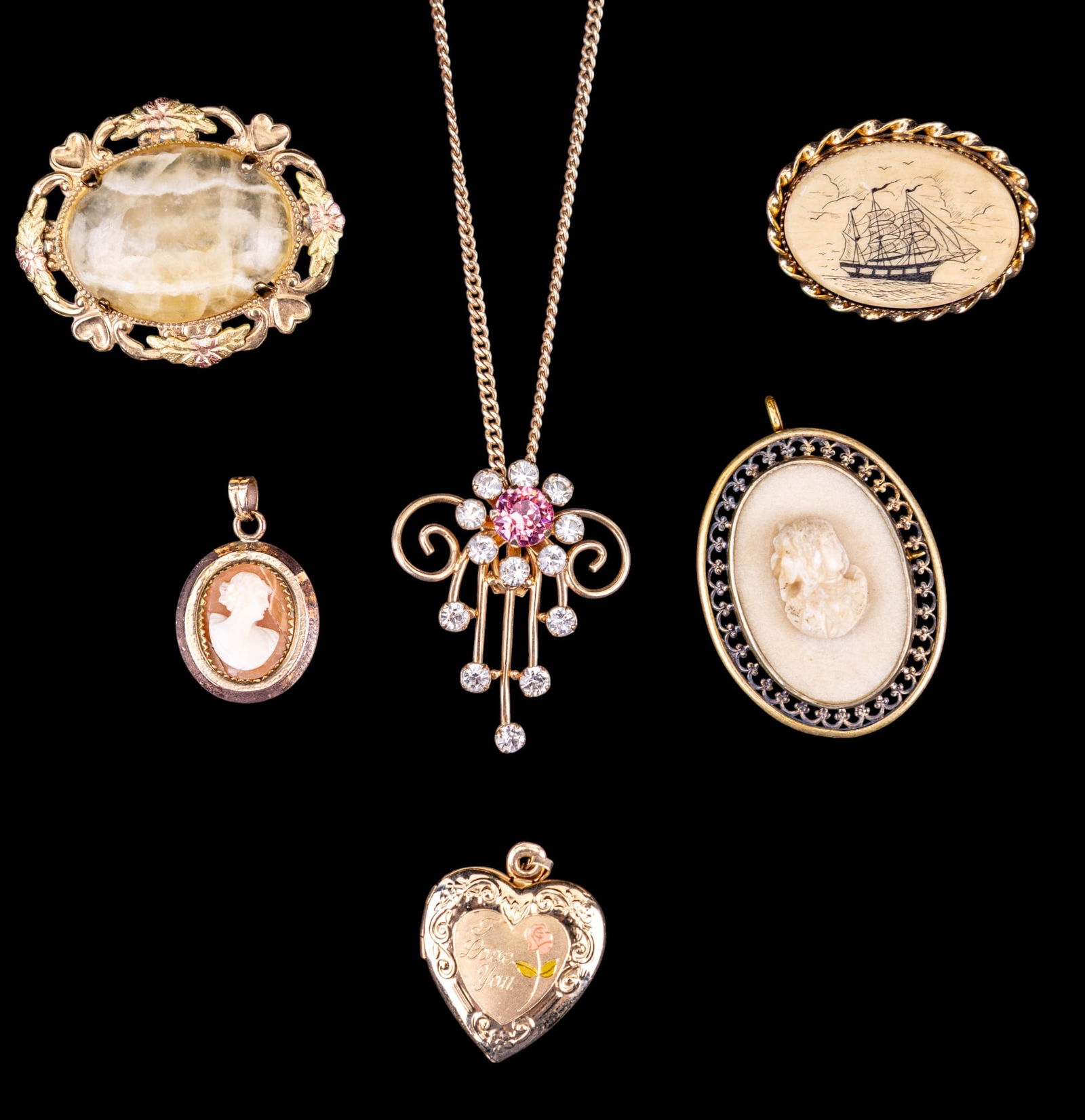 Van Dell, Hayward, and Other Gold Filled Jewelry: A collection of gold filled jewelry featuring a vintage filigree pendant with pink and clear floral rhinestone design, scrimshaw brooch, a 14K GF incised heart locket, a cameo style brooch/pendant, a