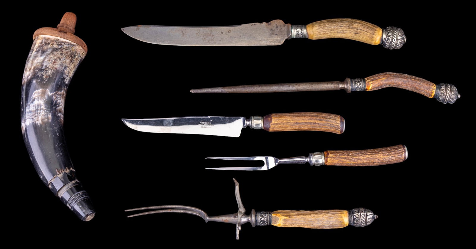 Antler Handle Carving Set and Powder Horn: Hand carved powder horn with wooden cap, a 3 piece set of Sheffield antler and silver plate handled carving cutlery, and a Russell Green River Works carving knife and fork set.