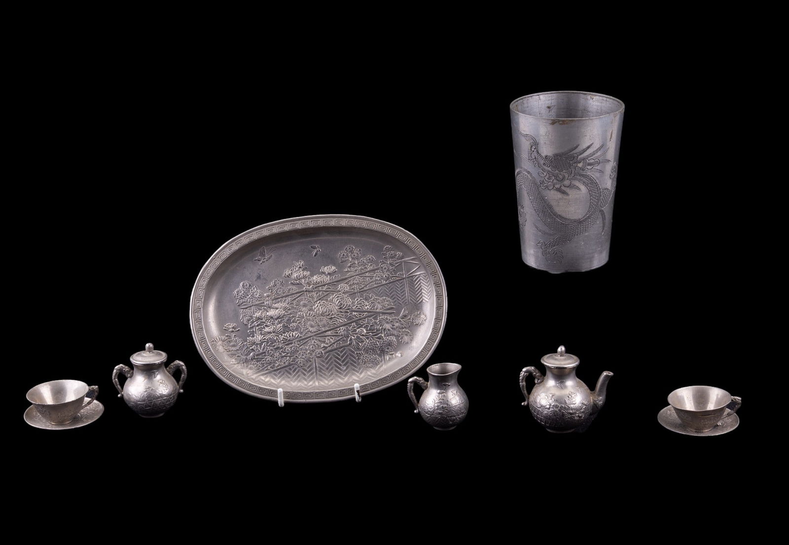 Etched Pewter Dragon Cup and Miniature Tea Set: Vintage etched pewter cup depicting a dragon with four toes, measures approx. 3" diam x 4" H, and a miniature embossed pewter tea set with chrysanthemum and butterfly motif.