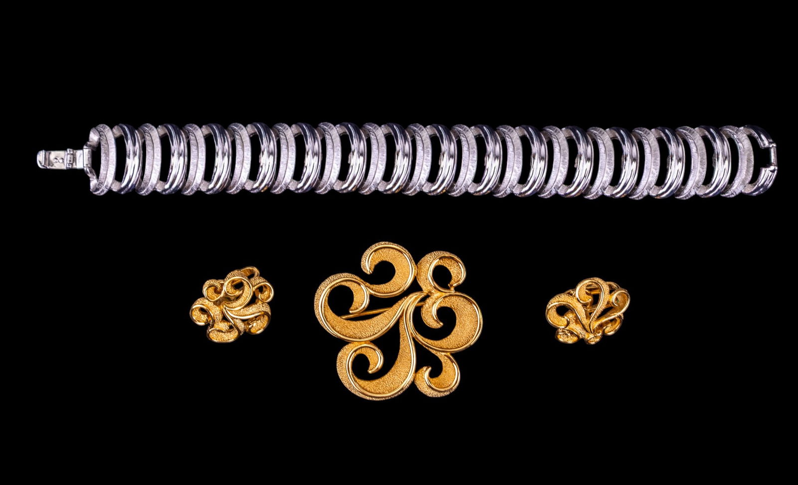 Vintage Trifari Jewelry: Includes a 3-piece gold tone swirl set and a silver tone bracelet, all signed Trifari.