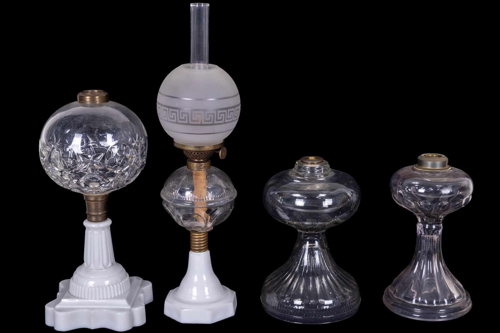 Attr. Boston & Sandwich Glass Co. Oil Lamps: Group of 4 clear and milk glass oil lamps, each attributed to the Boston & Sandwich Glass Company. Includes 2 ribbed clear glass examples. One with pressed starburst globe on a molded milk glass base,