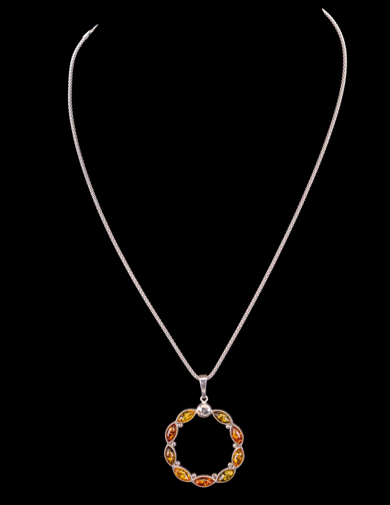 Amber and Sterling Silver Necklace: A multi stone circle style amber pendant set in sterling silver with a sterling silver 18" L chain.