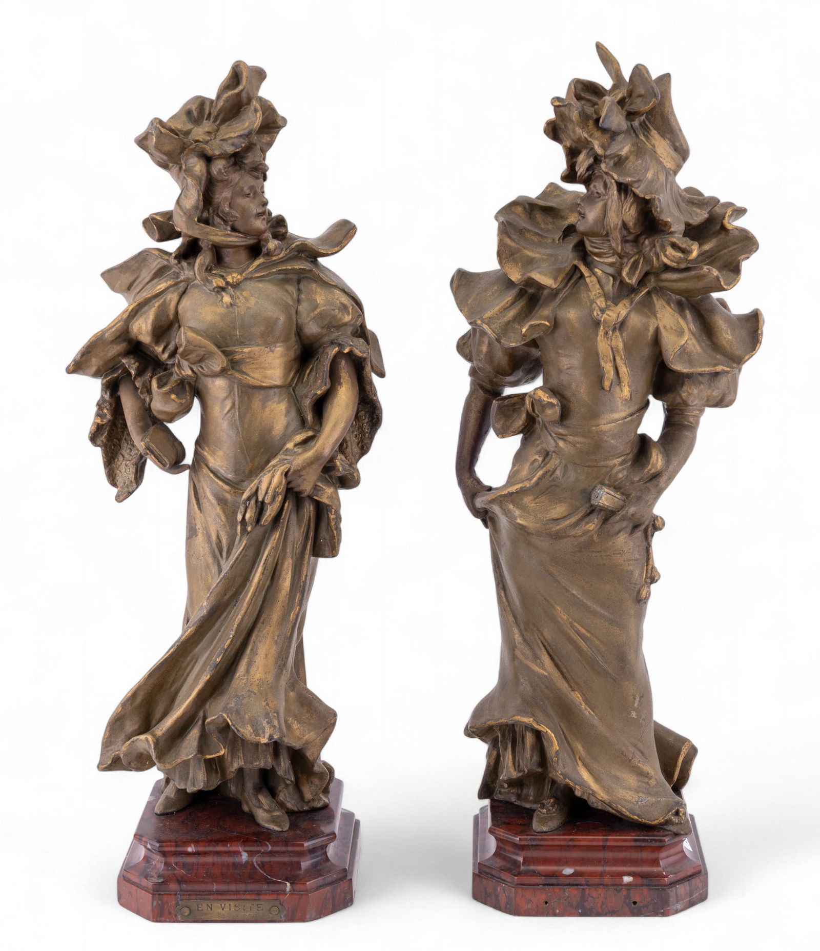 A. Nelson Antique Art Nouveau Figures (2): A companion pair of antique statues / statuettes depicting elegant (French) women Victorian dress, with label / titled "En Visite par A. Nelson". Each figure is shown in dynamic pose with flowing garm