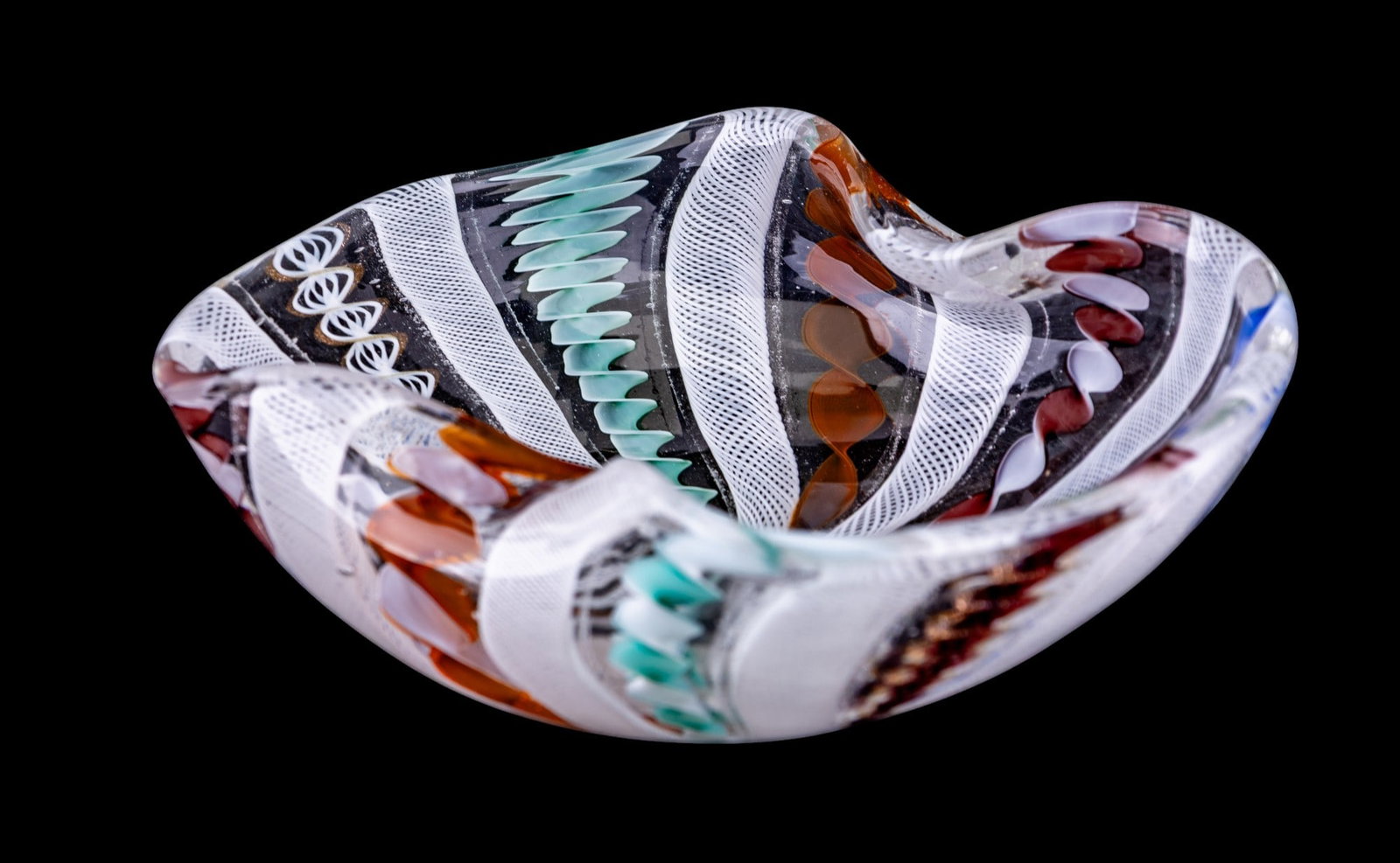 Murano Latticino Ribbon Art Glass Bowl: Hand-blown Murano art glass bowl with undulating rim, featuring alternating latticino ribbon and twisted multicolor cane designs encased in clear glass. Measures approx. 6" W.