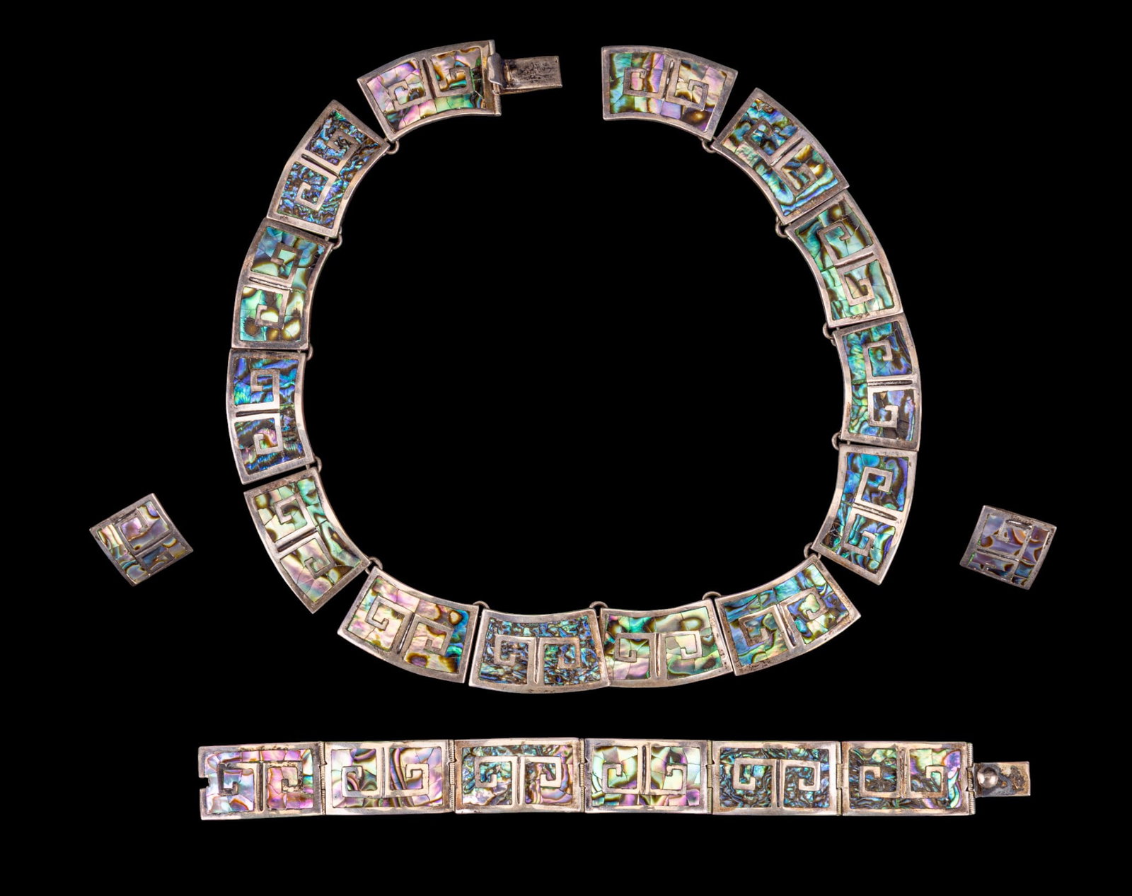 Sterling & Mother-of-Pearl Jewelry Set: Sterling silver jewelry set comprising a necklace, bracelet, and a pair of earrings, each formed from articulated rectangular links inlaid with mother-of-pearl and featuring geometric motifs. Each pie