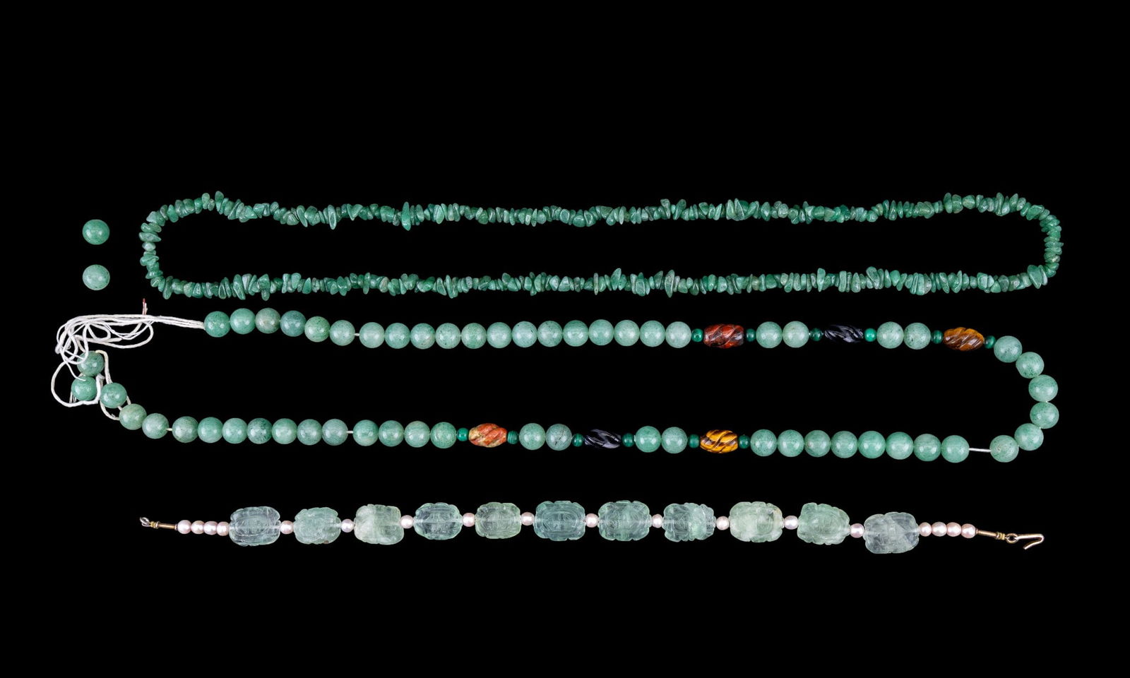 Natural Jade Necklaces: Collection of natural jade necklaces featuring a strand of rough tumbled jade beads, a strand of spherical polished jade beads featuring onyx, tiger's eye, malachite, and jasper beads, and a fine carv