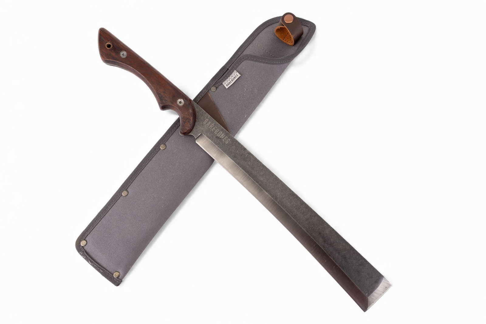Barebones Brand Machete in Sheath: Barebones forged steel machete featuring a straight spine, sharpened edge, with hardwood handle. Measures approx. 19.25" total length.