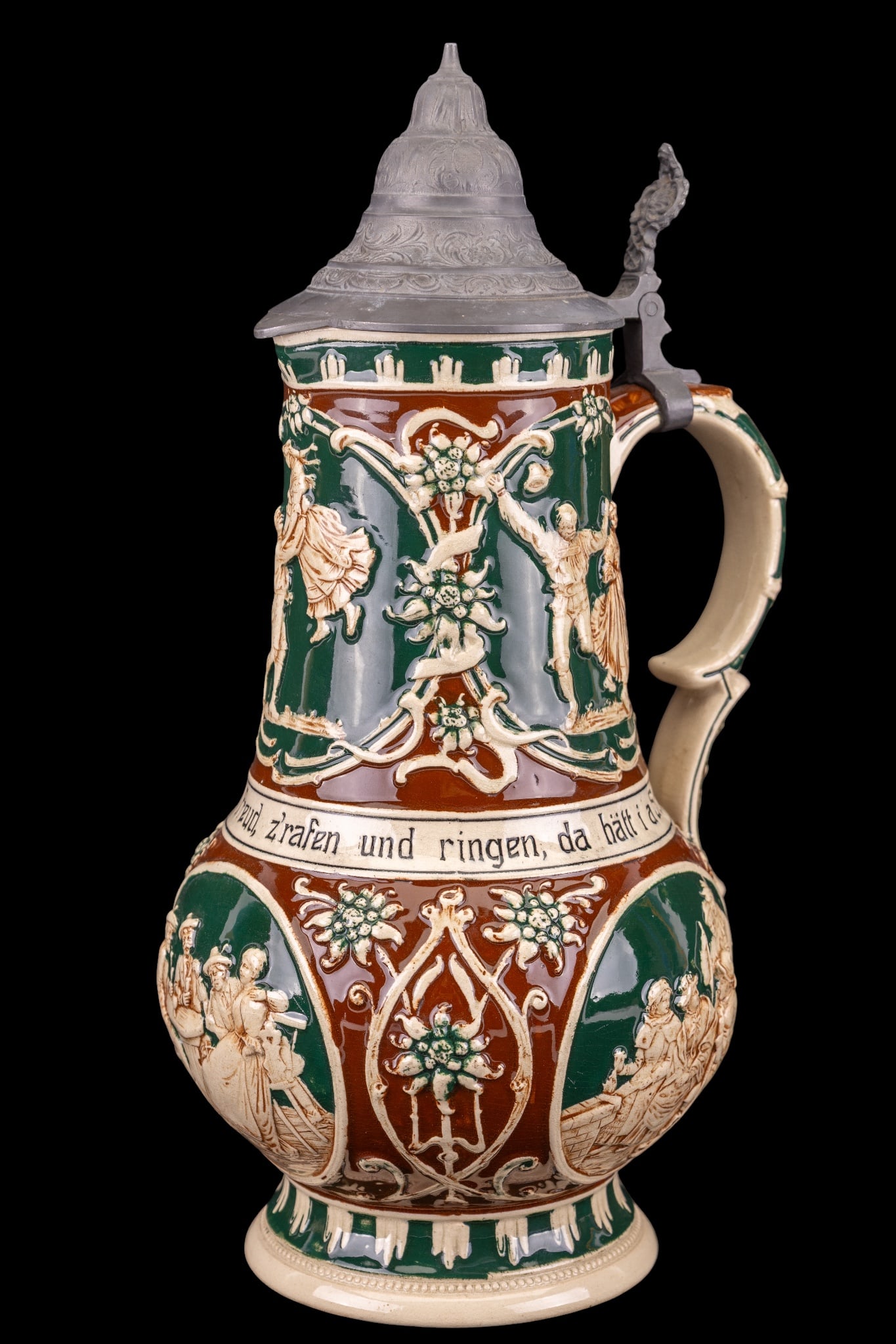 Large German Pottery Beer Stein w/ Pewter Lid: German pottery beer stein, marked Germany and mold number 872 on the base. High-relief figural decoration featuring dancers, musicians, and tavern scenes against a green and brown glaze. Band of Germa