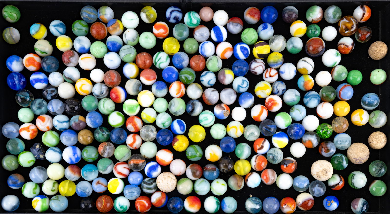 Vintage Glass and Clay Marbles: Assortment of vintage marbles, including opaque, transparent, and swirl-pattern glass examples, along with several early clay marbles. Wide variety of colors and patterns.