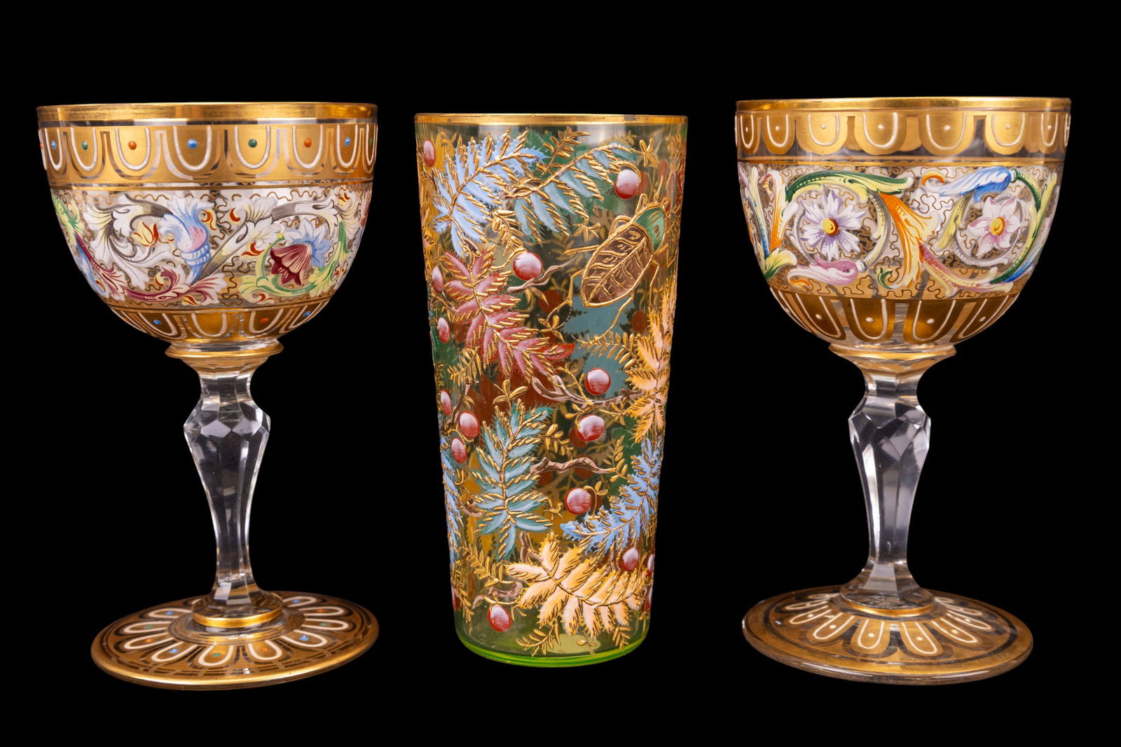 Bohemian Stemware and Uranium Drinking Glasses: Includes 2 matching enameled Bohemian goblets with gilt accents, together with one gilt and polychrome Uranium glass tumbler decorated with leaves, insects, and berries. Each goblet / wine cordial mea