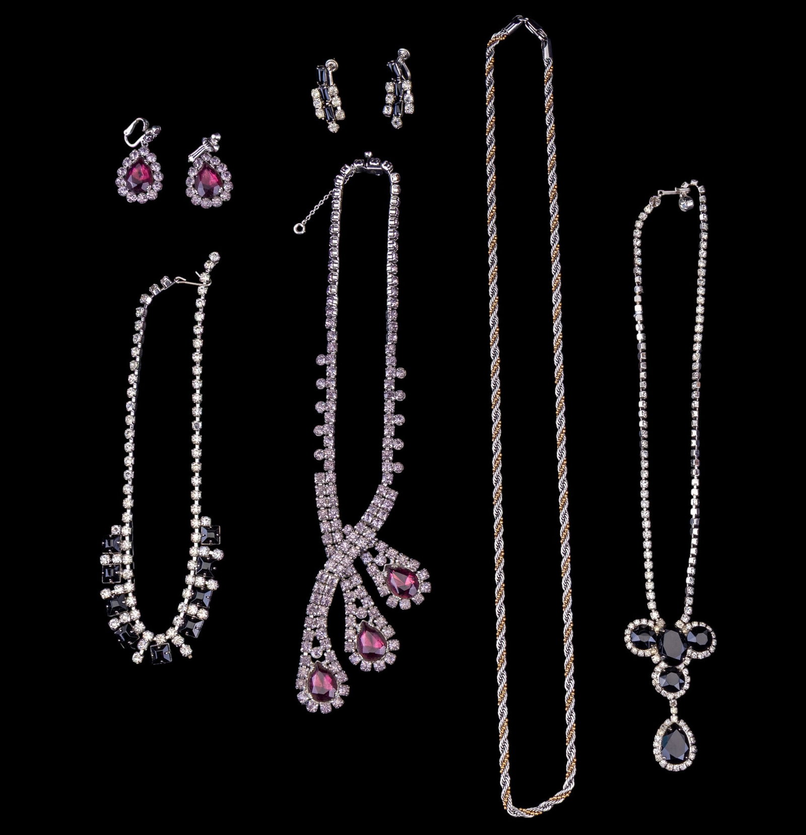 Vintage Rhinestone Jewelry Sets: A collection of jewelry sets including a clear and purple tear drop rhinestone statement necklace with matching clip on drop earrings, a clear and black baguette rhinestone necklace with matching scre